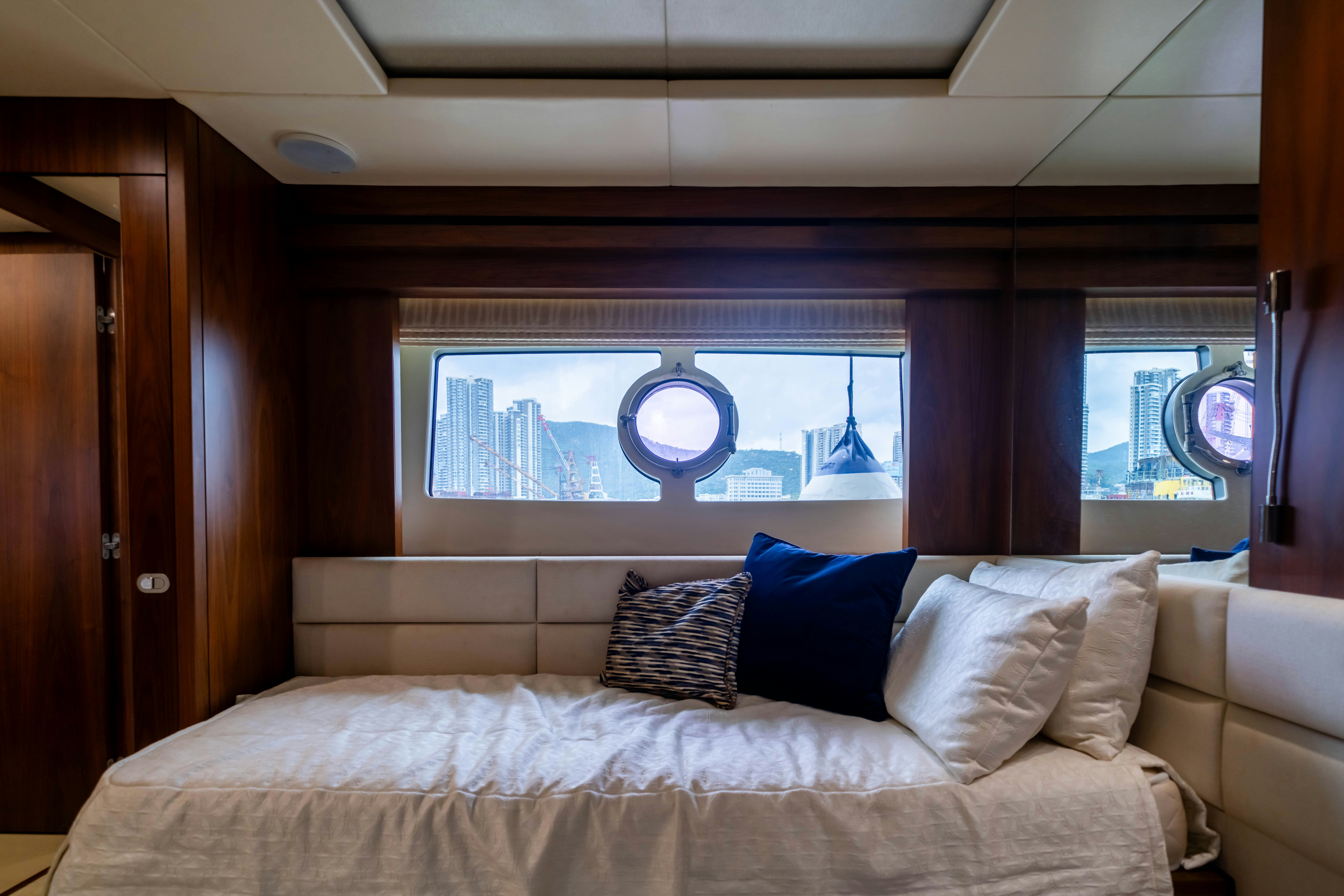 a bed with pillows and a window aboard DRAGON Yacht for Sale