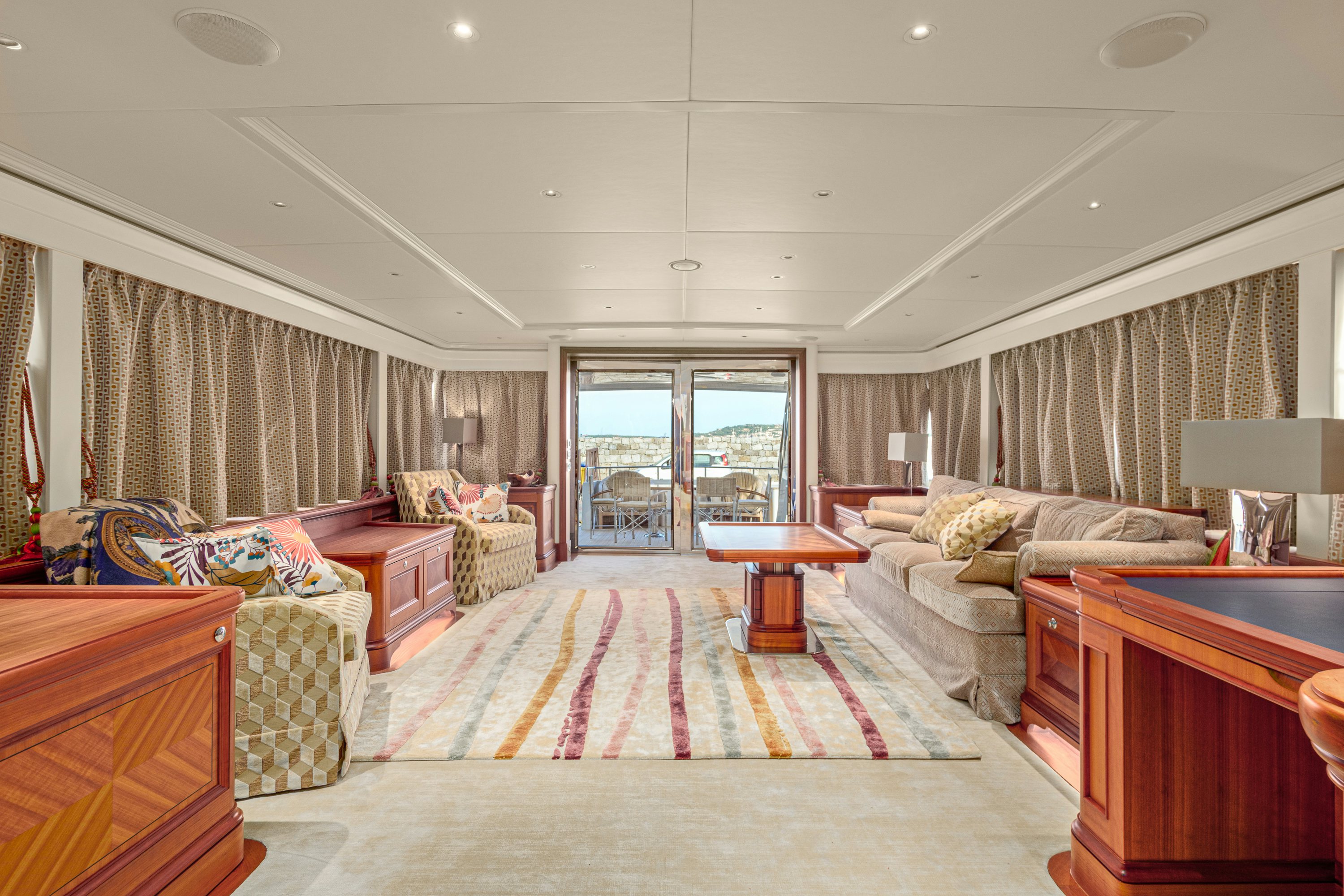 a large living room with a red rug aboard FRIVOLOUS Yacht for Sale