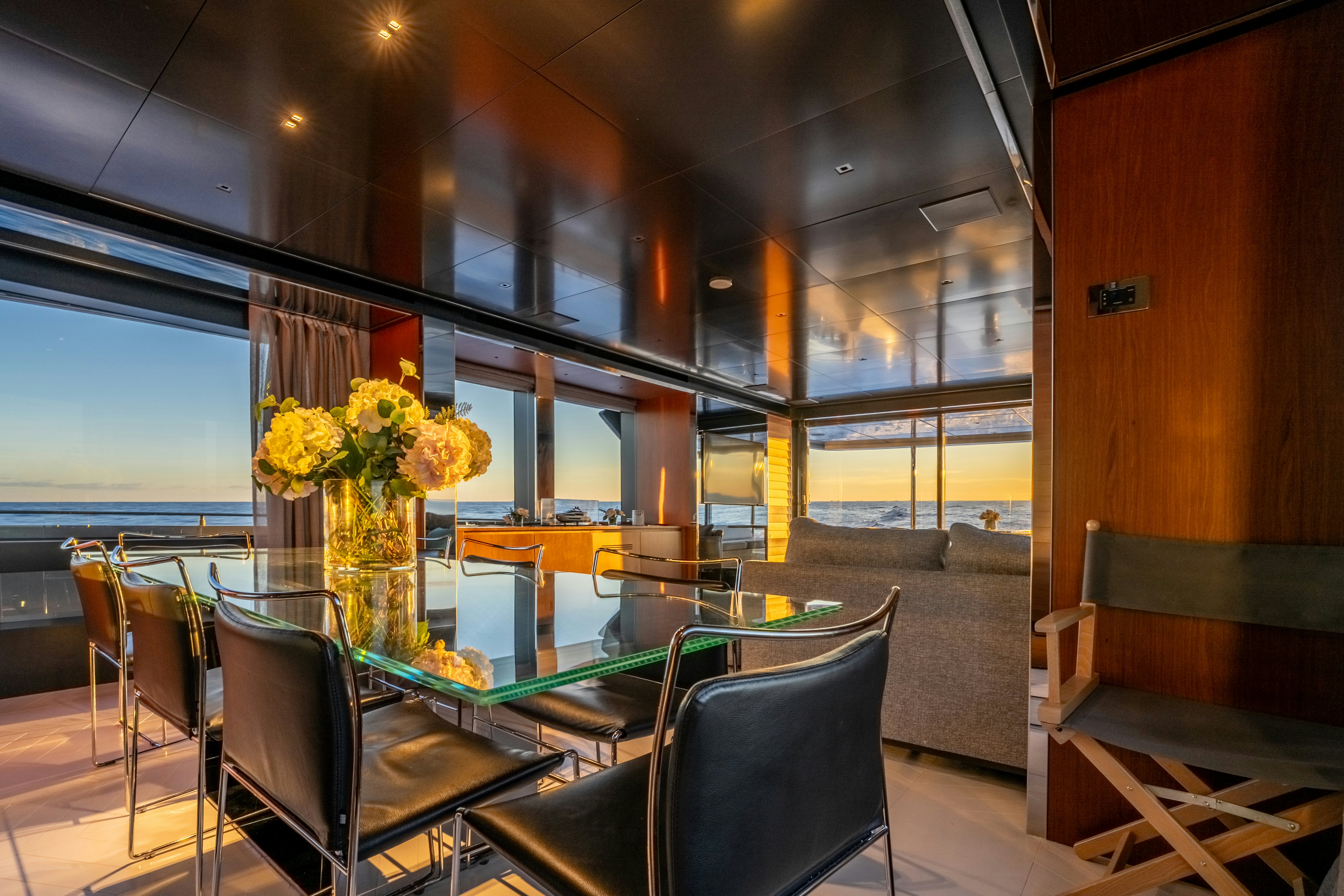 a room with a table chairs and a vase with flowers in it aboard NOI Yacht for Sale