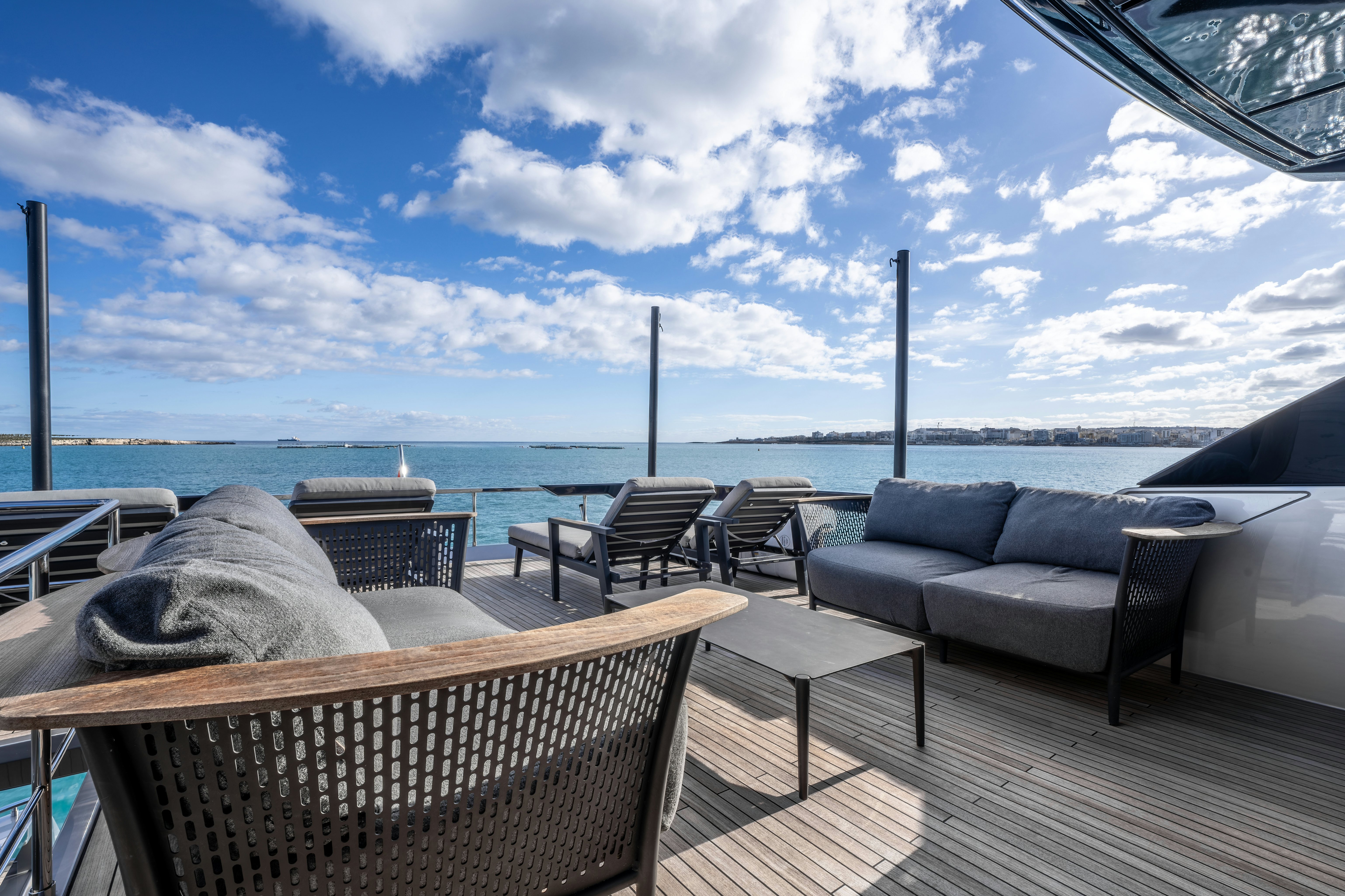 a deck with chairs and a body of water in the background aboard NOI Yacht for Sale
