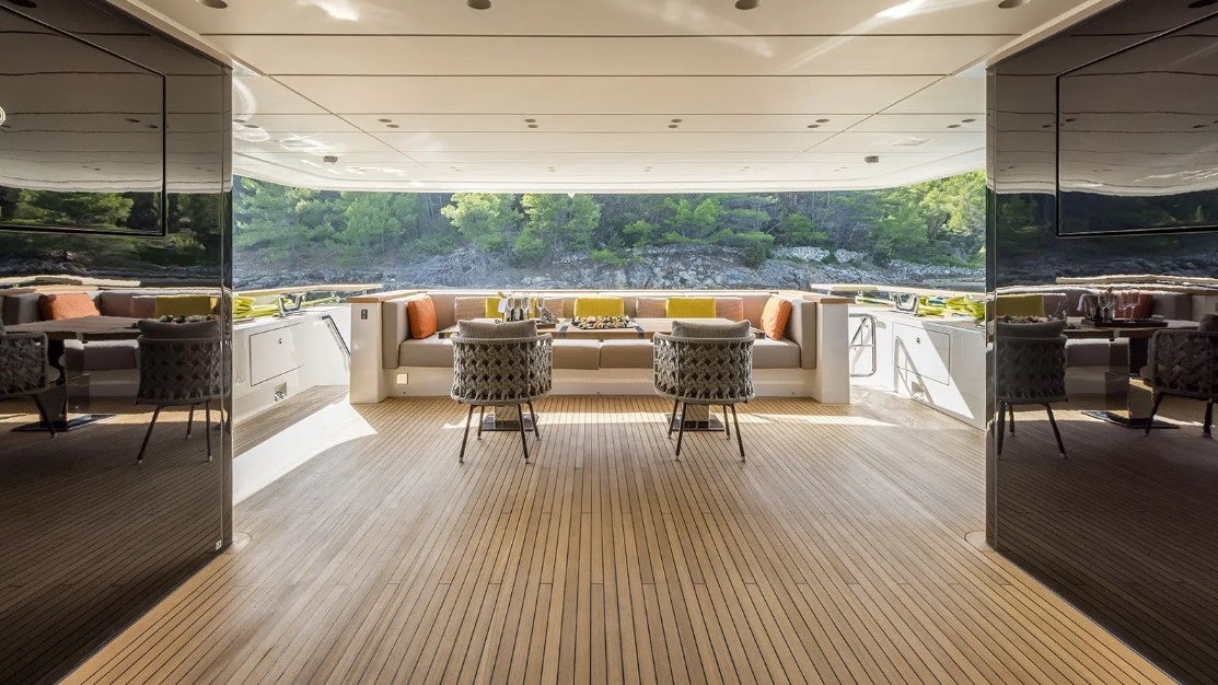 a room with a wood floor and chairs and a large window aboard ANDIAMO Yacht for Charter