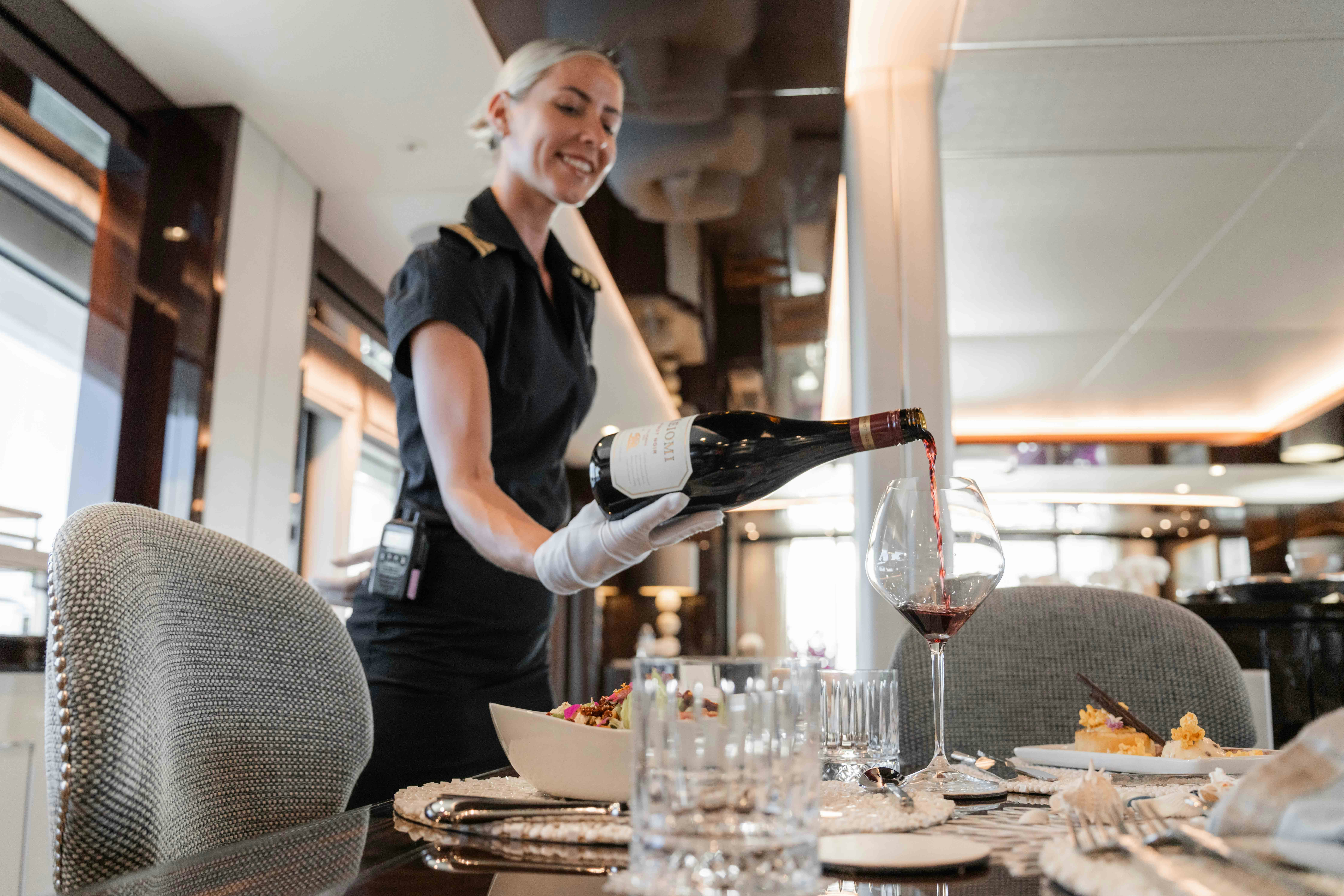 a person pouring wine into a glass aboard CAPTAIN MORGAN III Yacht for Charter