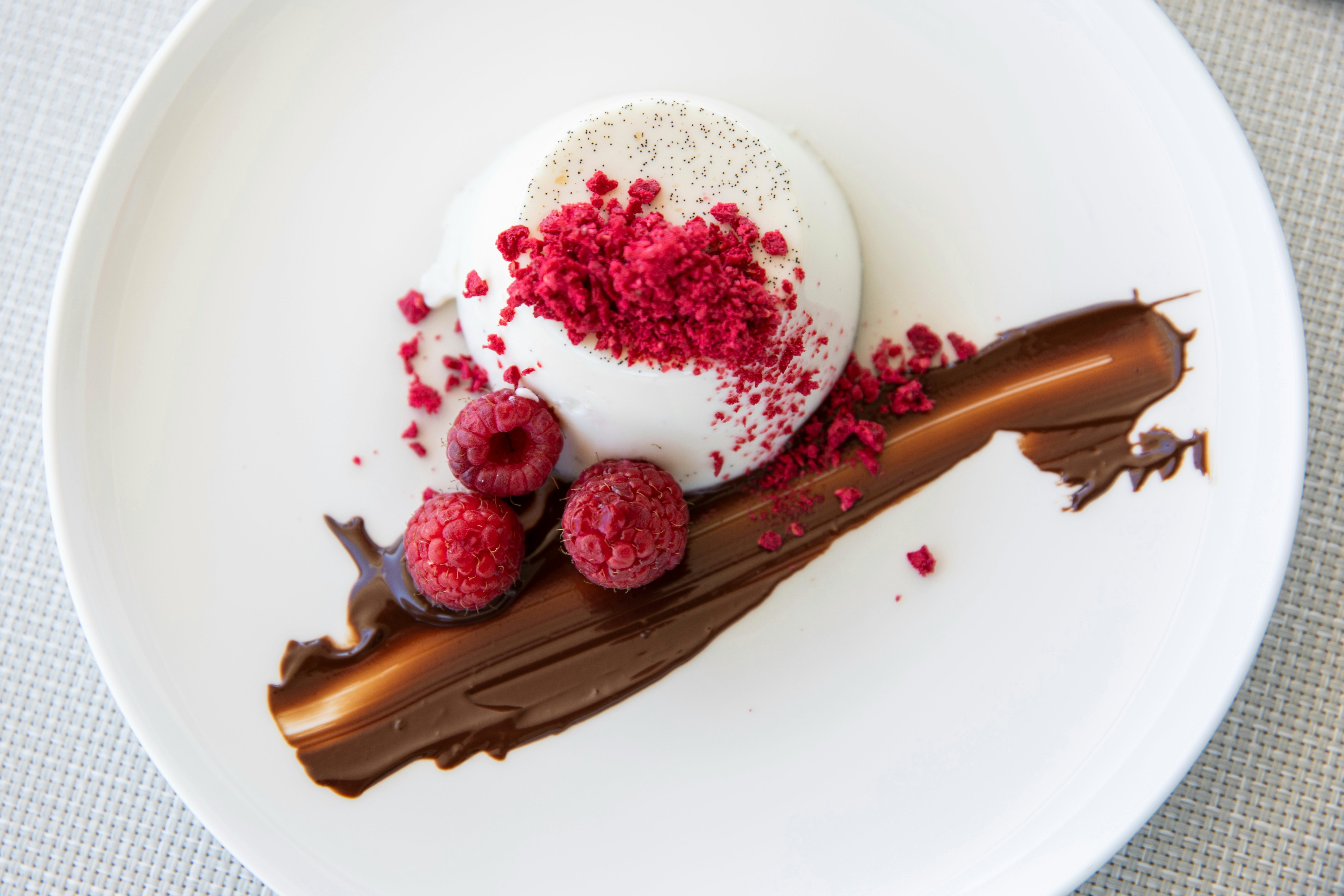 a plate with a piece of cake and raspberries on it aboard MOKA Yacht for Charter