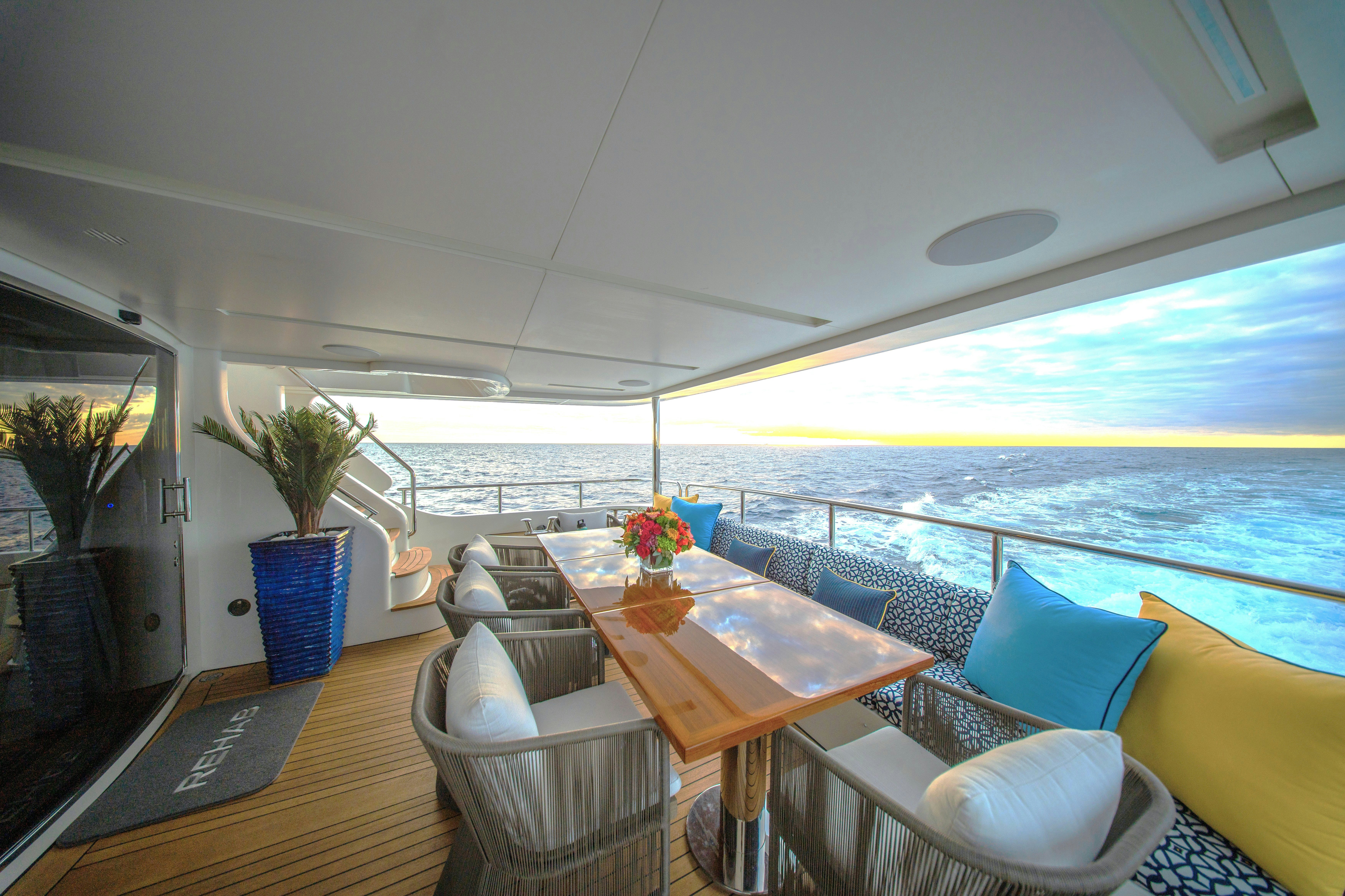 a room with a table chairs and plants on the side aboard REHAB Yacht for Sale