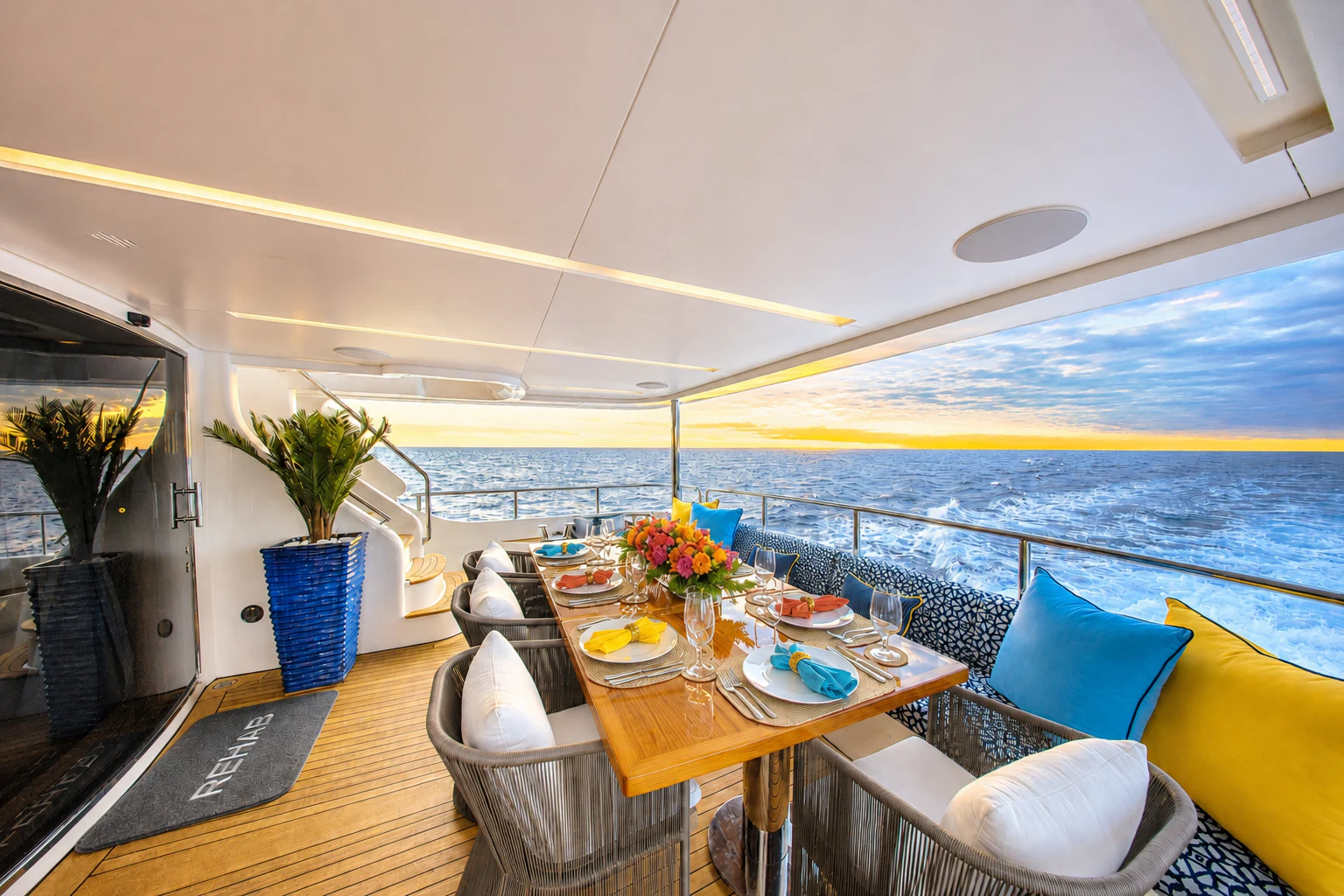 a dining table with chairs and a view of the ocean aboard REHAB Yacht for Sale