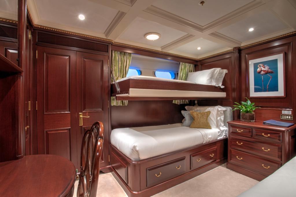 a bedroom with a bed and a dresser aboard TELEOST Yacht for Charter