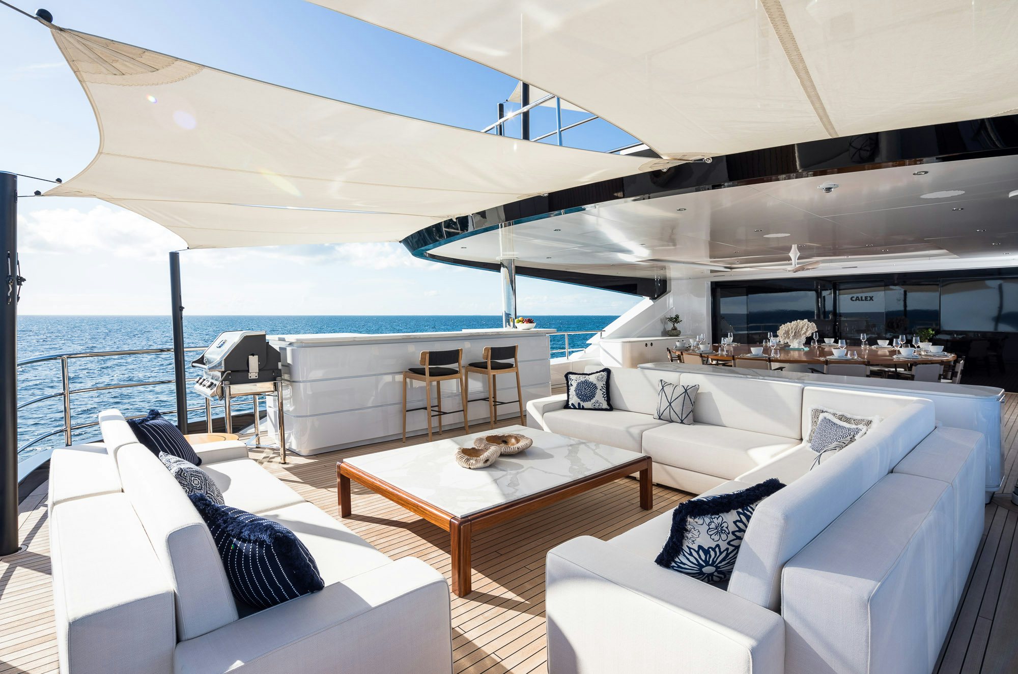 a room with a couch and a table and a large body of water aboard CALEX Yacht for Charter