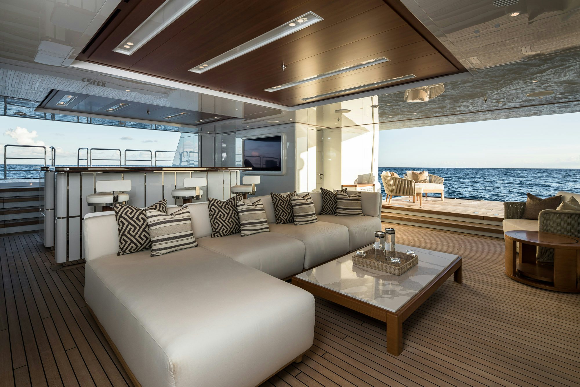 a living room with a large sofa and a large blue ocean aboard CALEX Yacht for Charter