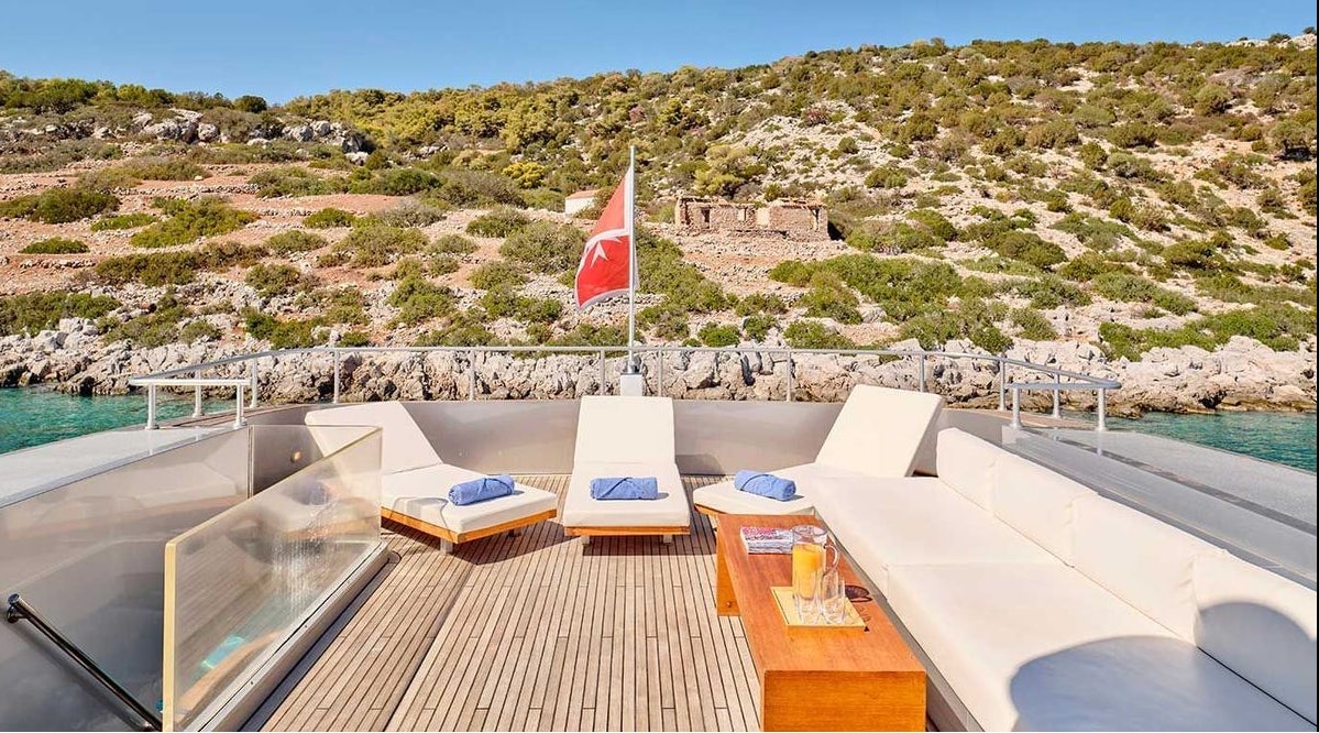 a deck with a flag and a body of water in the background aboard AMICI PER SEMPRE Yacht for Charter