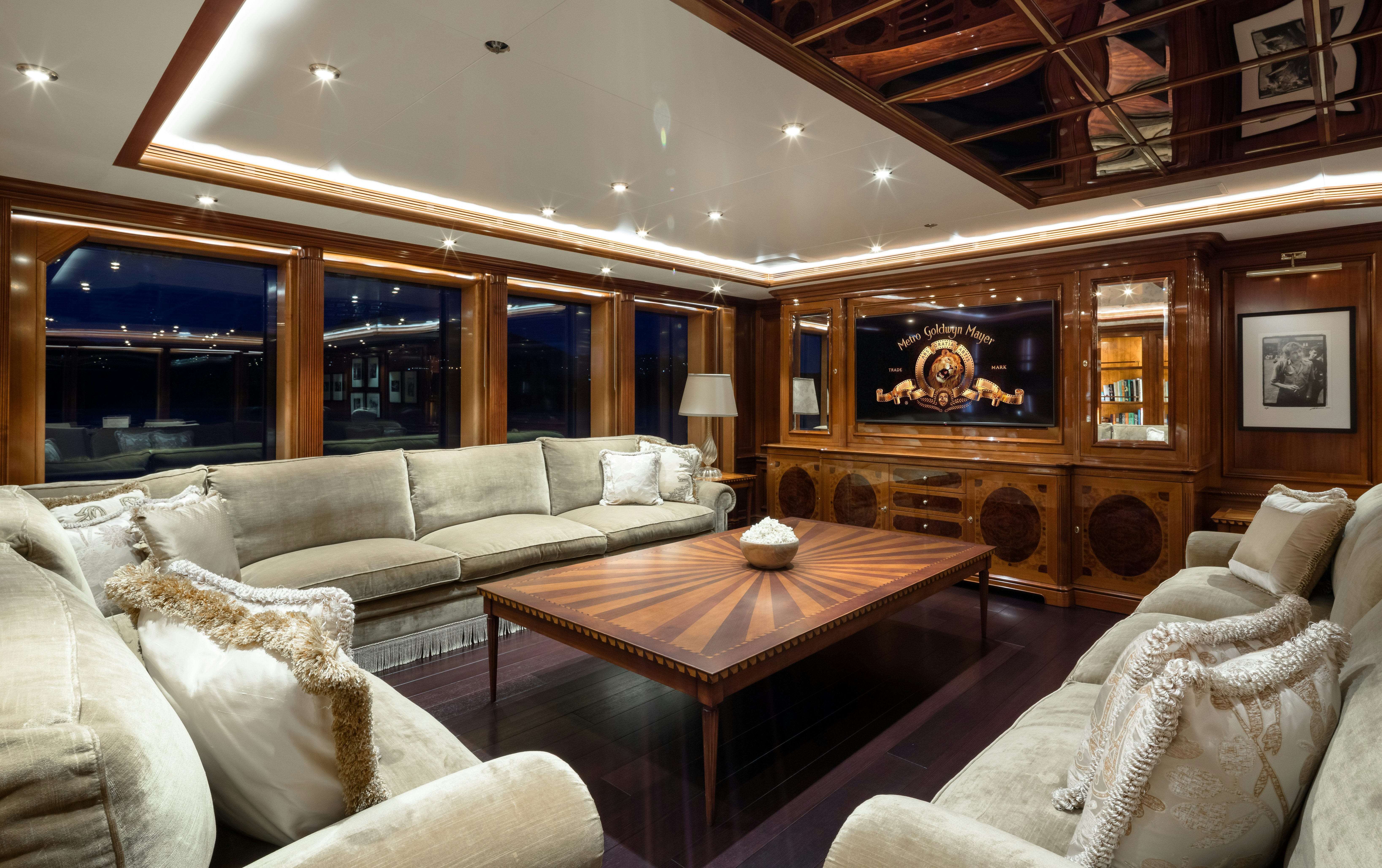 a living room with a large wood table and a large window aboard STARFIRE Yacht for Charter