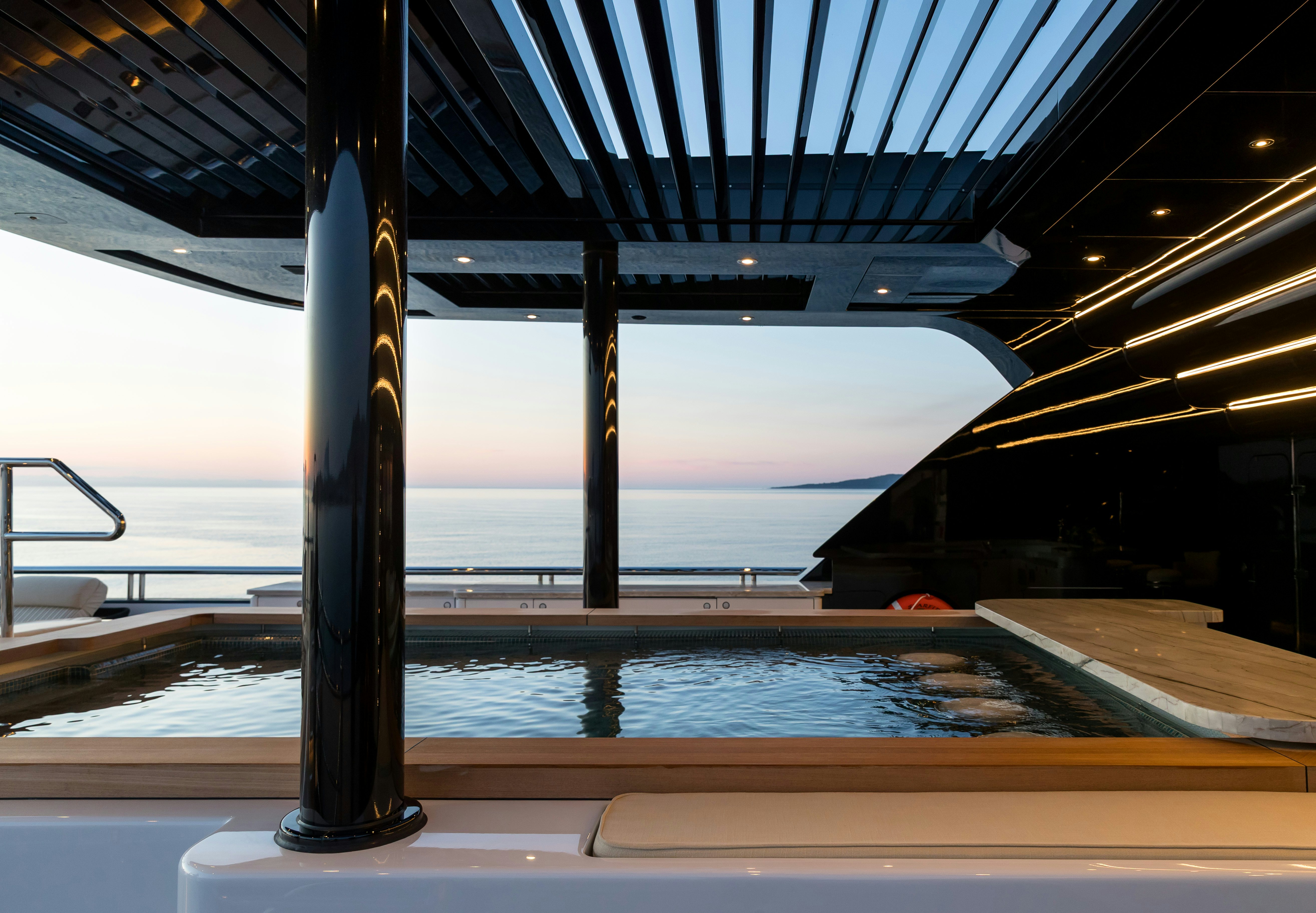a pool with a deck and a view of the water aboard STARFIRE Yacht for Charter