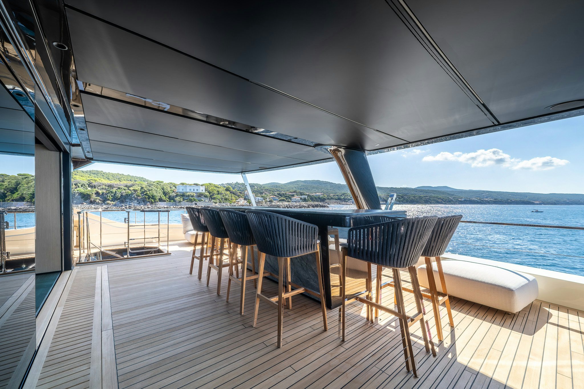 a deck with chairs and a body of water in the background aboard ACALI Yacht for Sale
