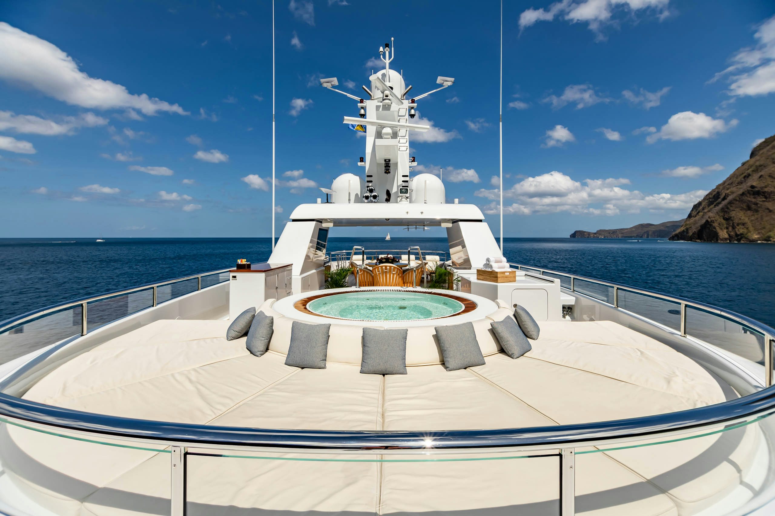 a white boat on a body of water with a white tower and blue sky and clouds aboard HARLE Yacht for Charter