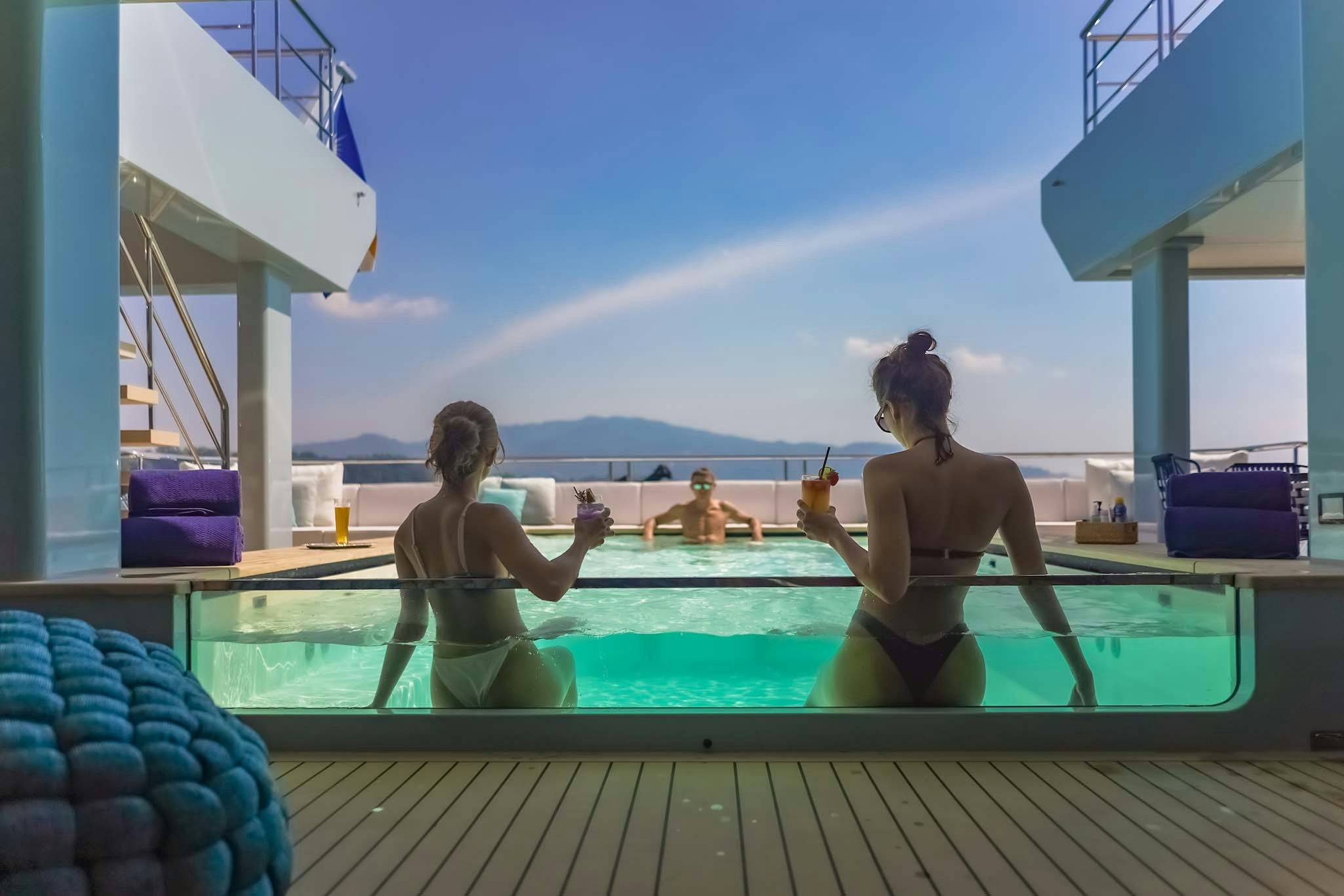 a couple of women sitting on a dock by a pool aboard SPACECAT Yacht for Charter