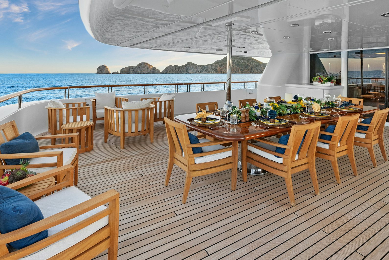 a wooden table with chairs on a deck overlooking a body of water aboard AMICA MEA Yacht for Charter
