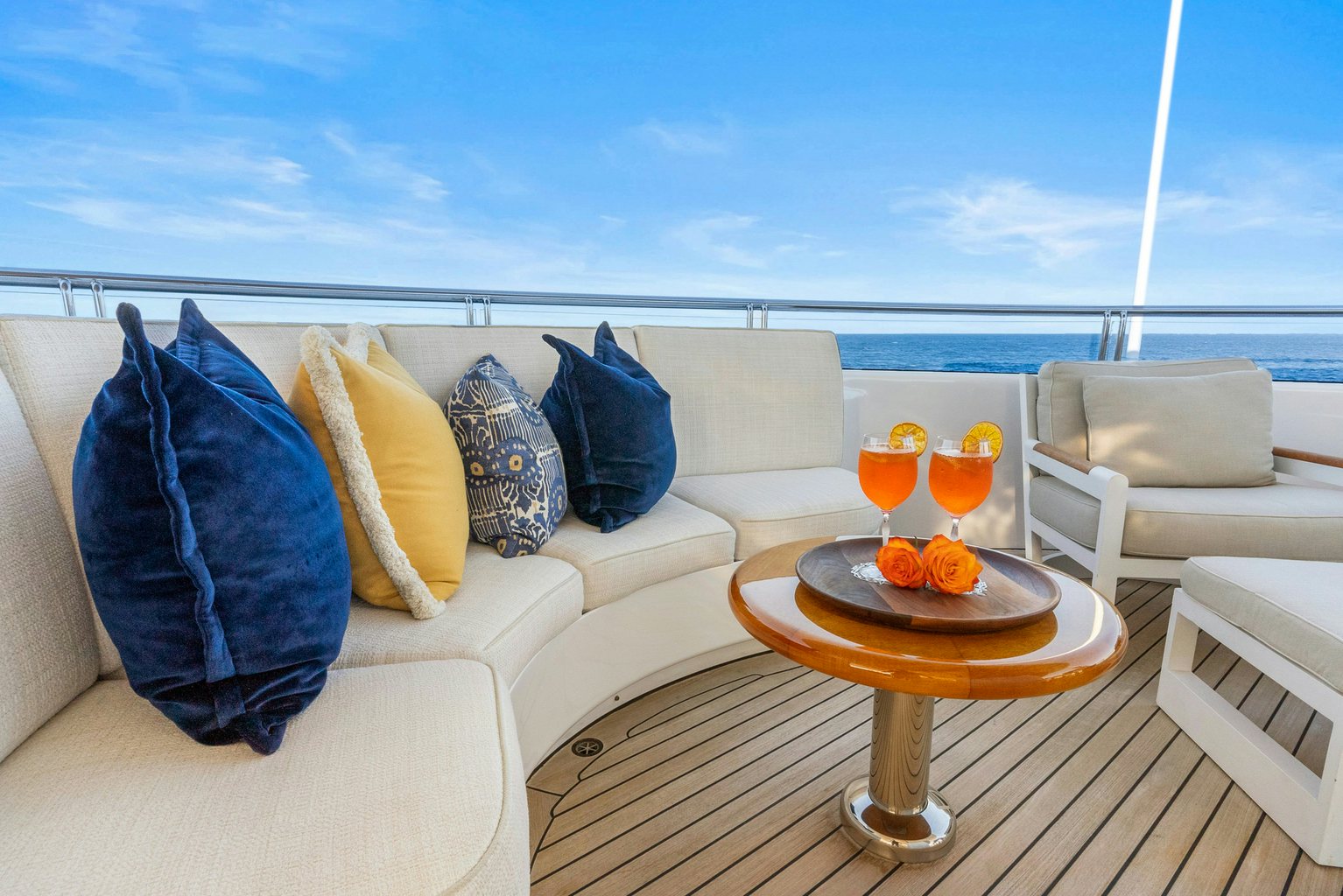 a couch with pillows and a table with a glass of orange juice on it aboard AMICA MEA Yacht for Charter