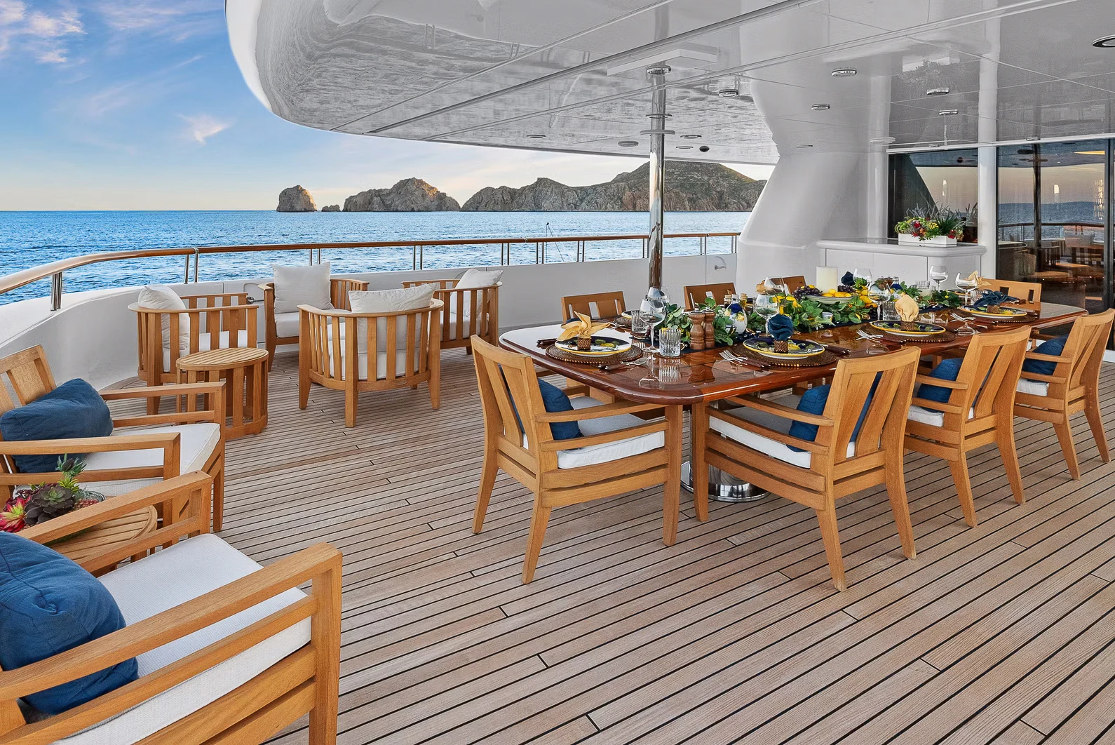 a wooden table with chairs on a deck overlooking a body of water aboard AMICA MEA Yacht for Sale