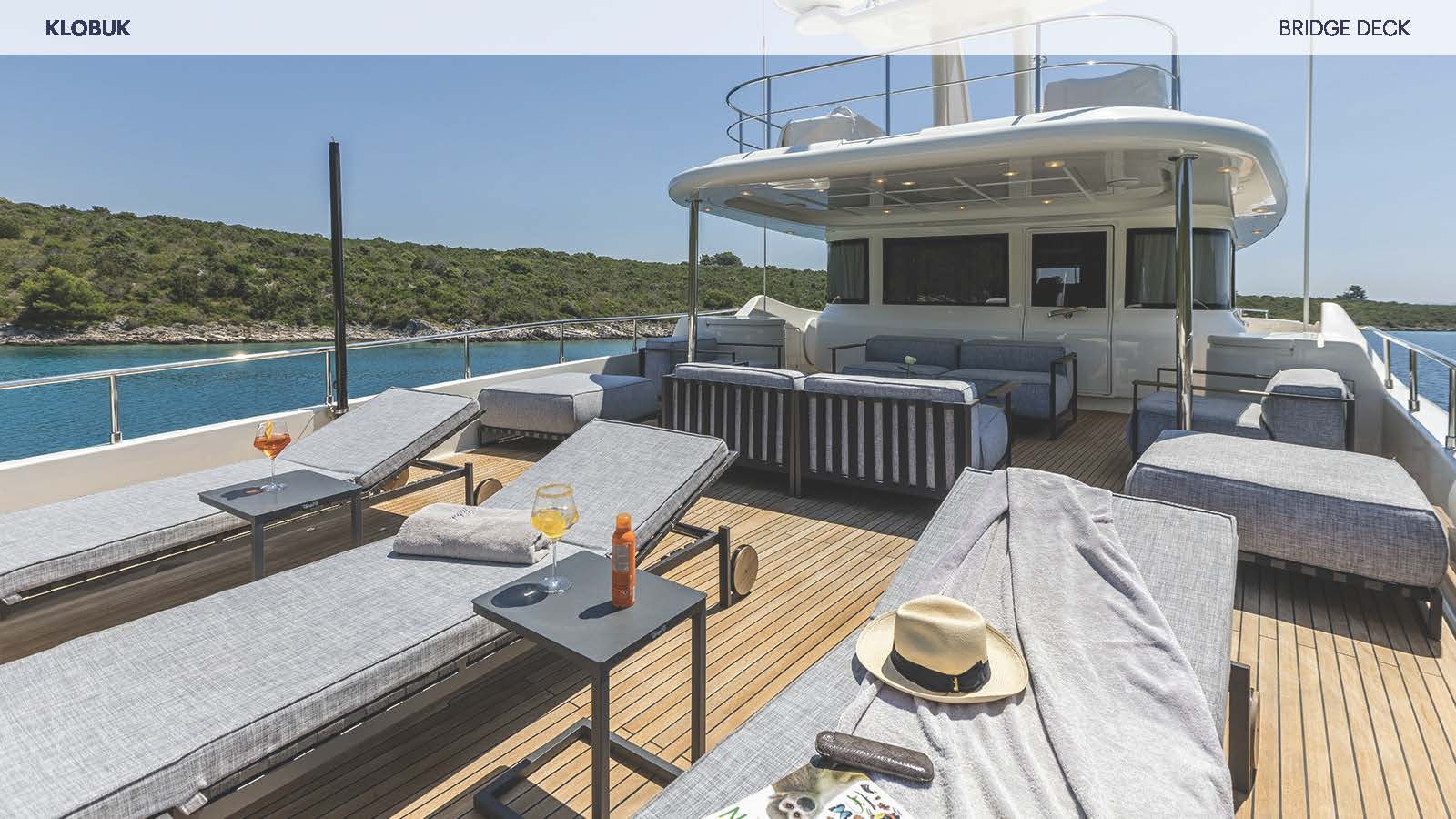 a deck with a table and chairs on it aboard KLOBUK Yacht for Charter