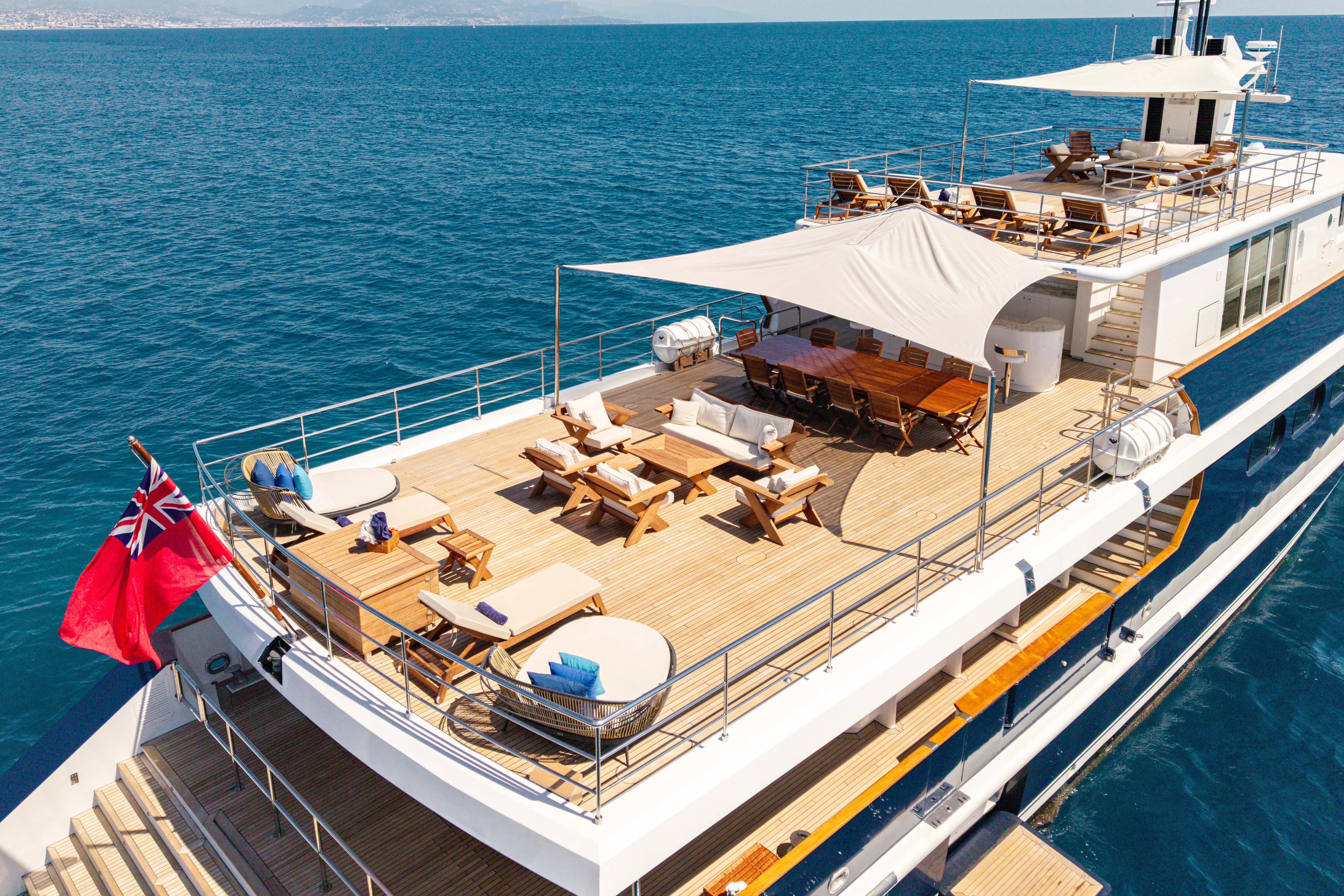 a deck with a large boat and chairs on it aboard KORU Yacht for Sale