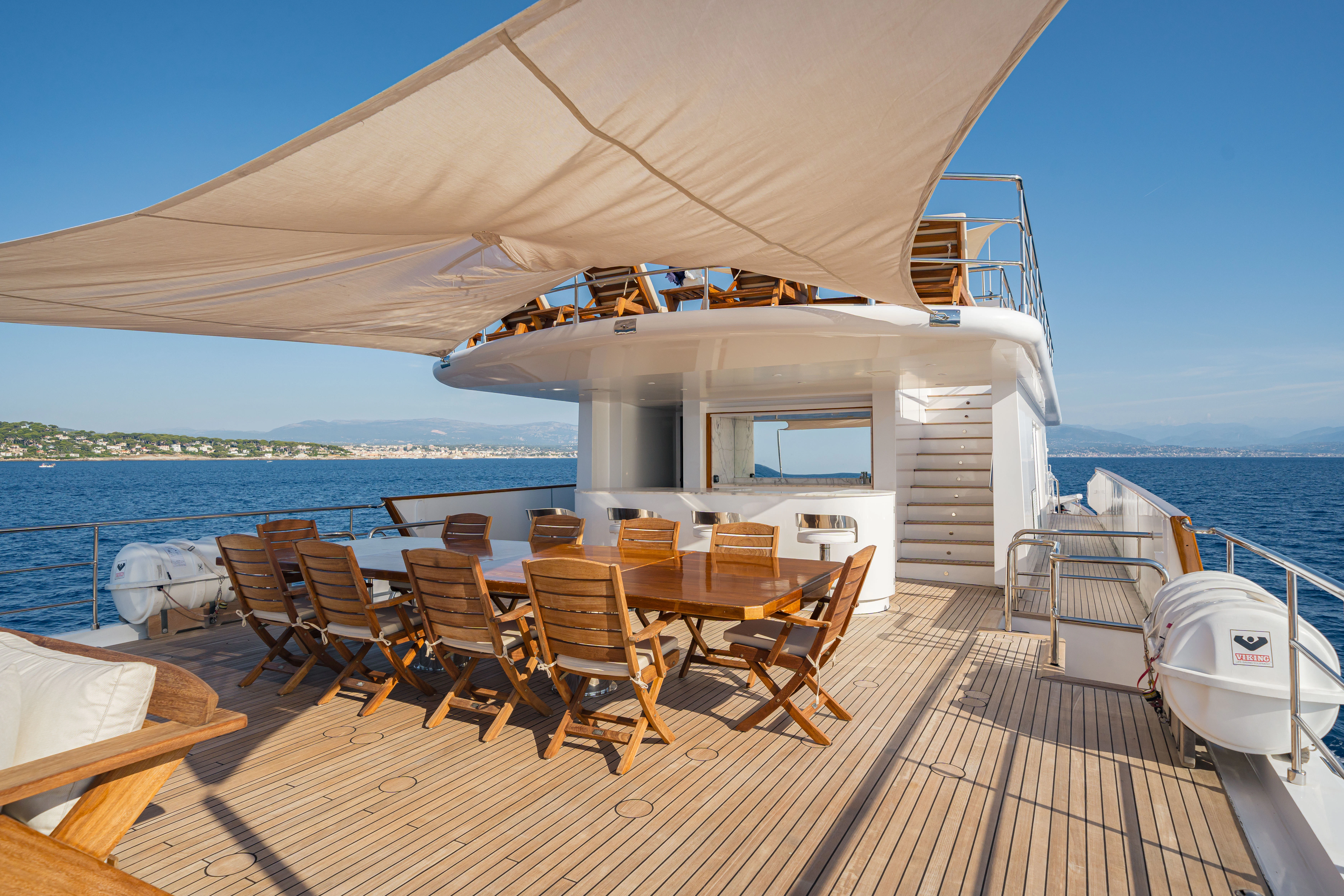 a deck with chairs and tables on it aboard KORU Yacht for Sale