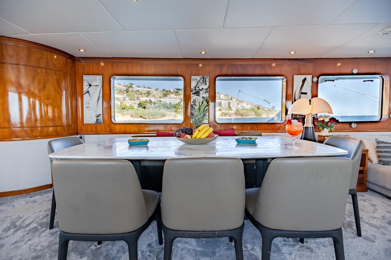 a table with chairs and a glass of wine on it aboard ALHAMBRA Yacht for Charter