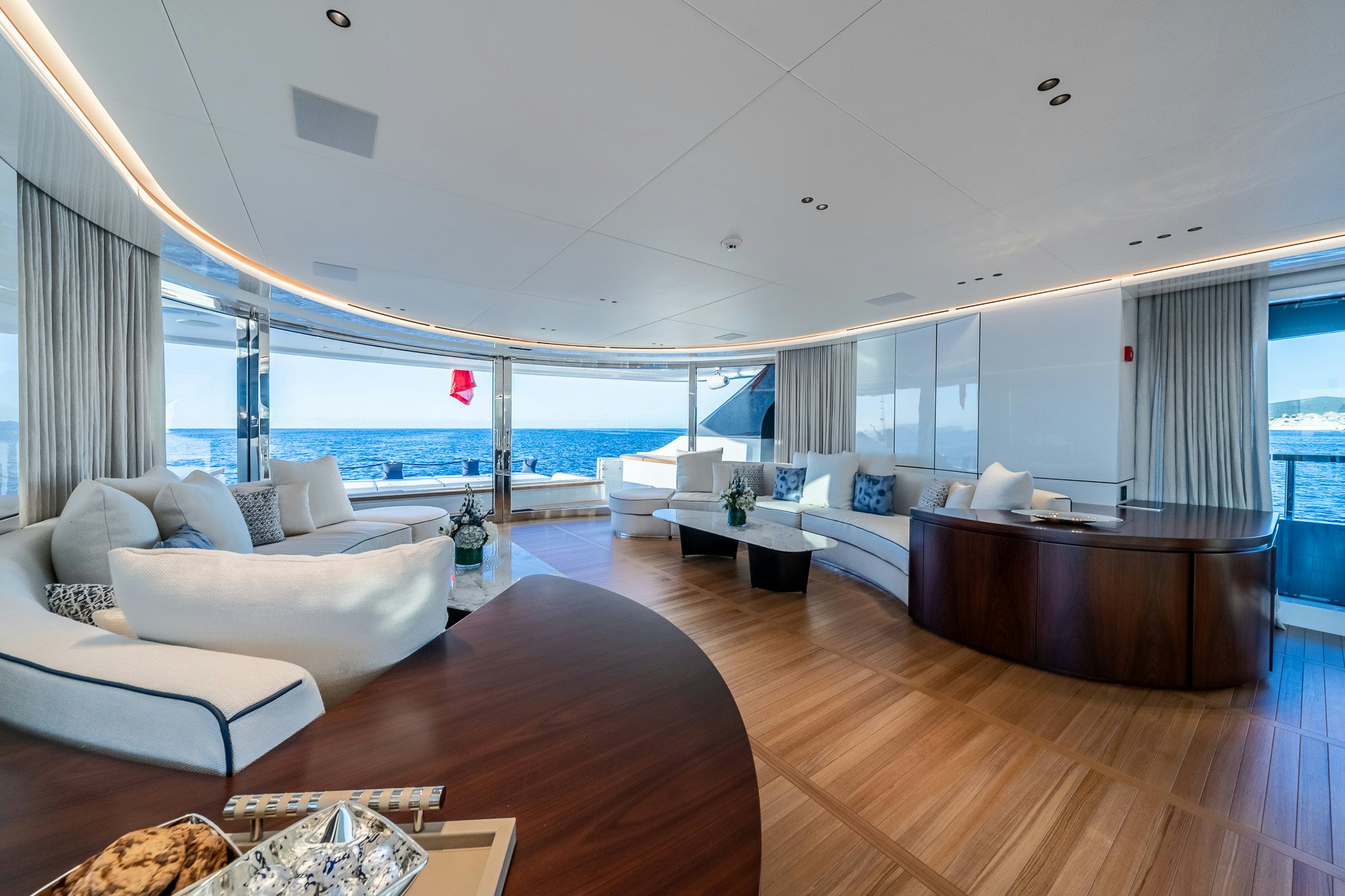 a room with a large window and a wood table with white couches aboard ALPHA WAVES Yacht for Charter