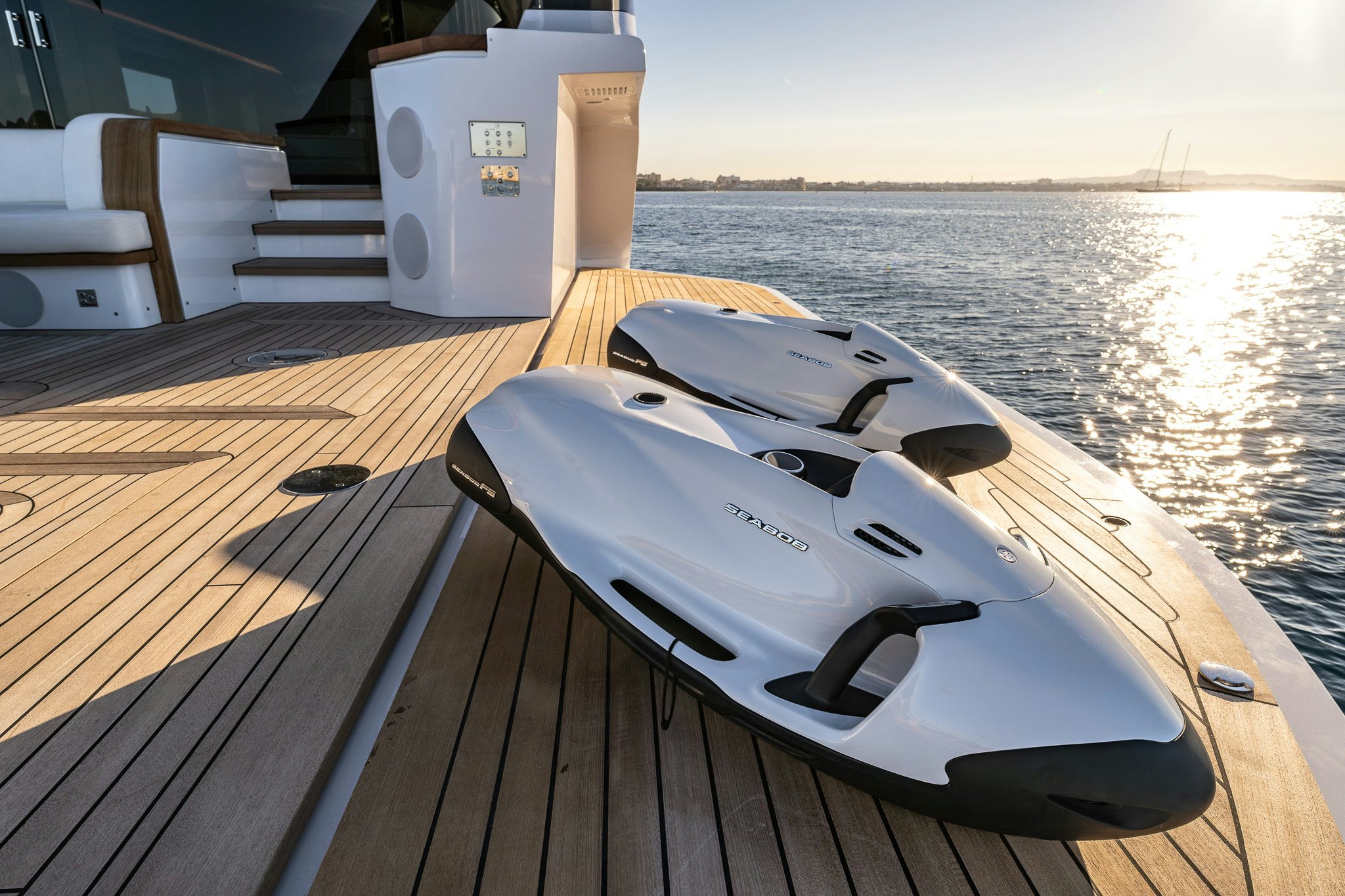 a white and black boat on a deck with a wood deck and a large body of water and aboard ALPHA WAVES Yacht for Charter