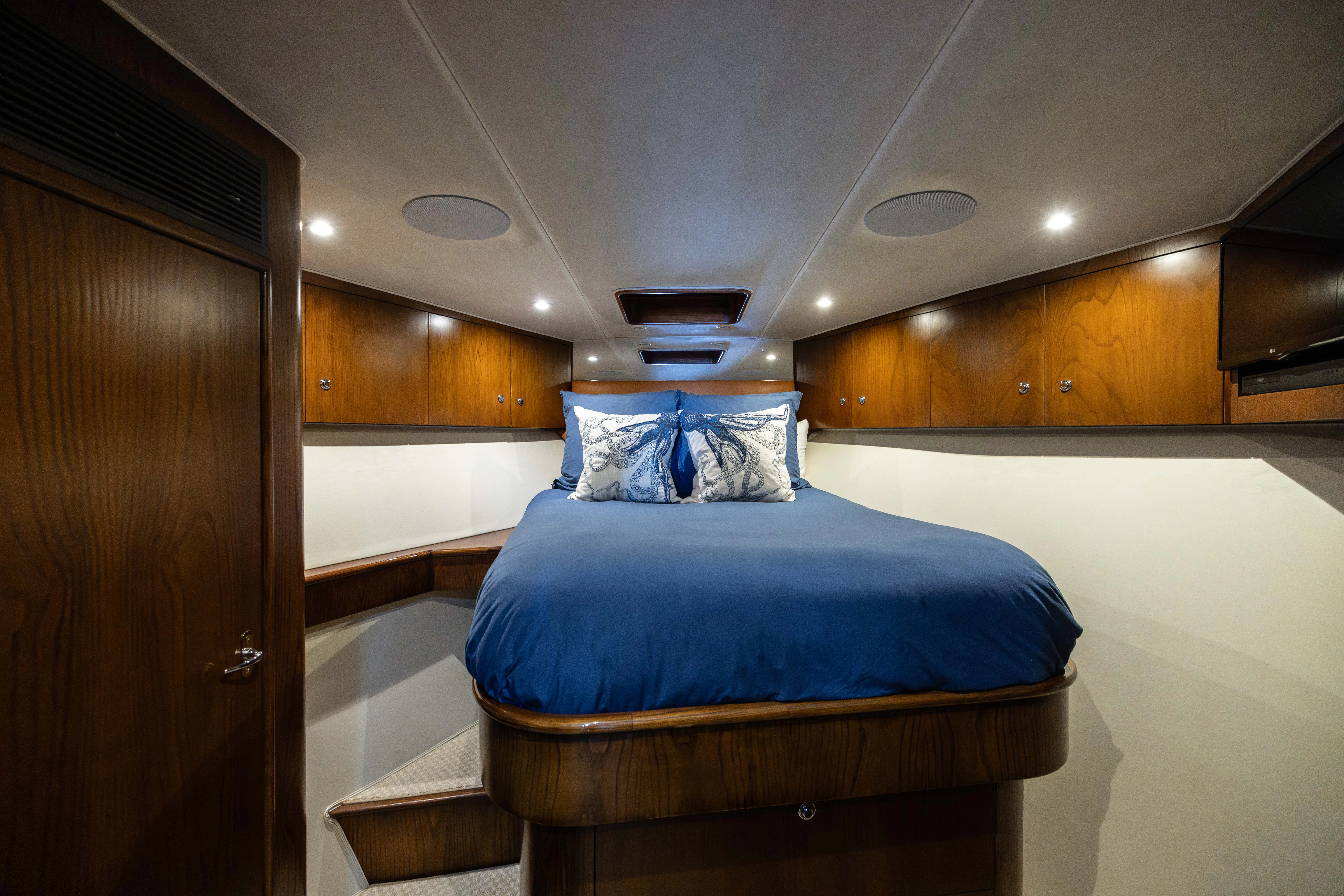 a bedroom with a bed and a wood cabinet aboard VERTIGO Yacht for Sale