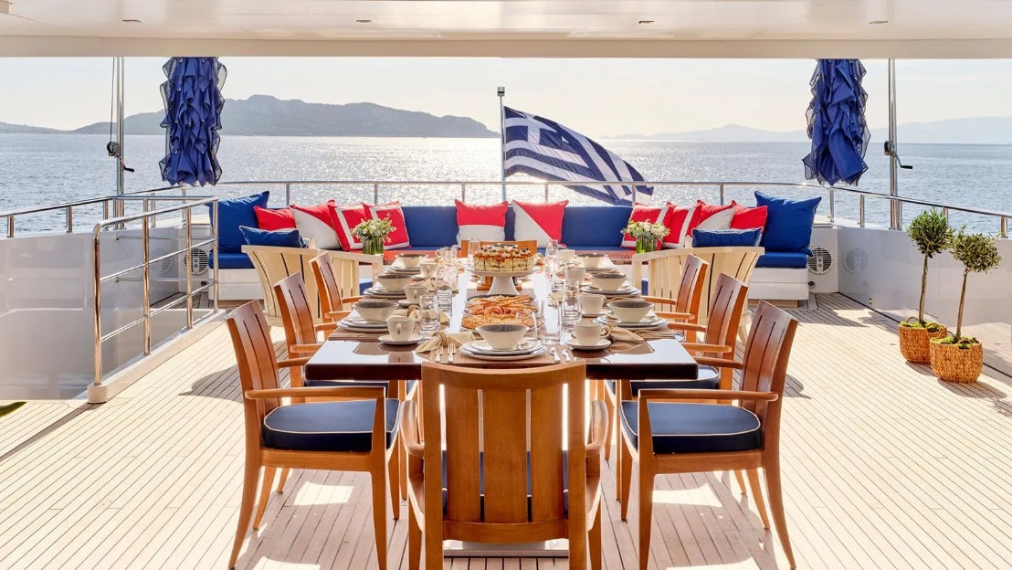 a table with chairs and a view of the ocean aboard TIMBUKTU Yacht for Charter