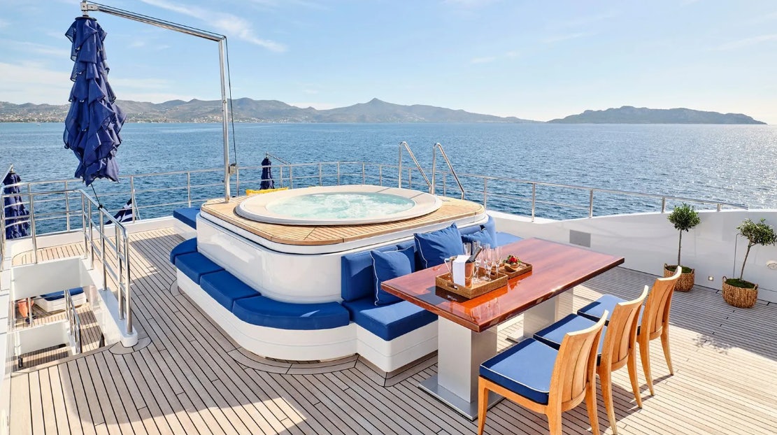 a table and chairs on a deck overlooking a body of water aboard TIMBUKTU Yacht for Charter