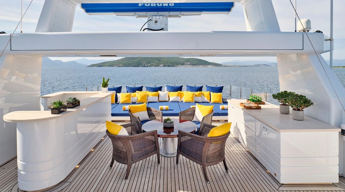a room with a table chairs and plants aboard TIMBUKTU Yacht for Charter