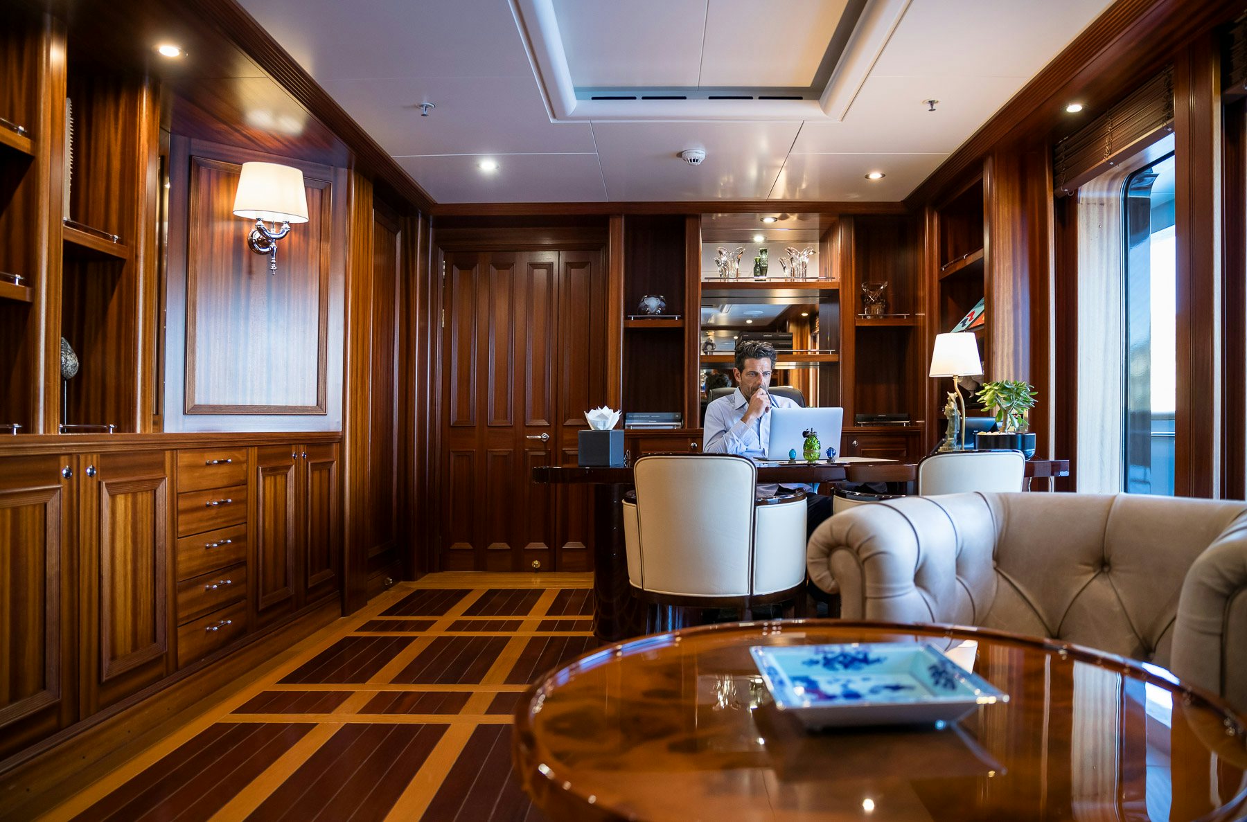 a person sitting at a table in a living room aboard BOADICEA Yacht for Charter