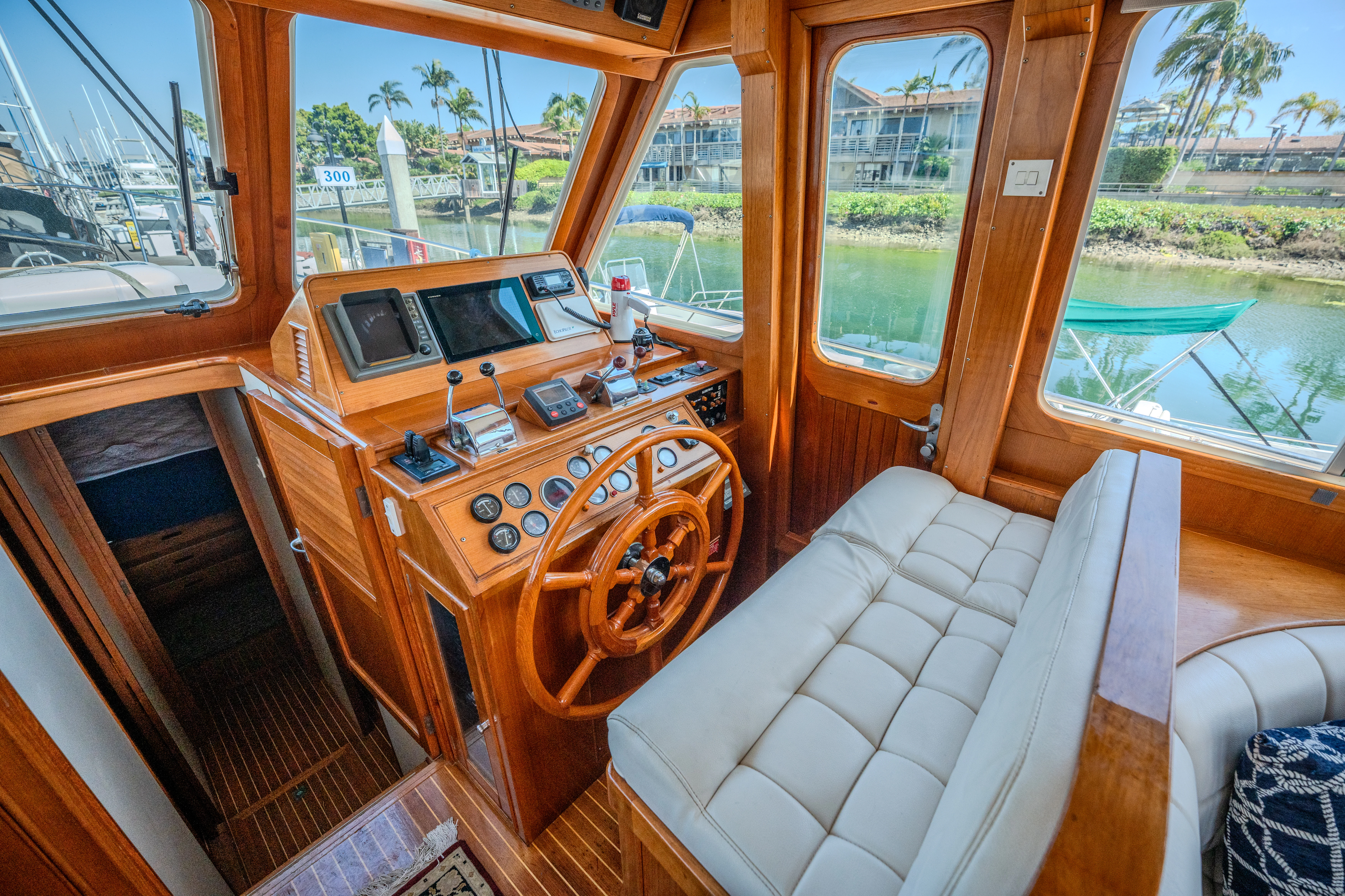 a wooden boat with a wood steering wheel and a white couch in front of a window aboard OSPREY Yacht for Sale