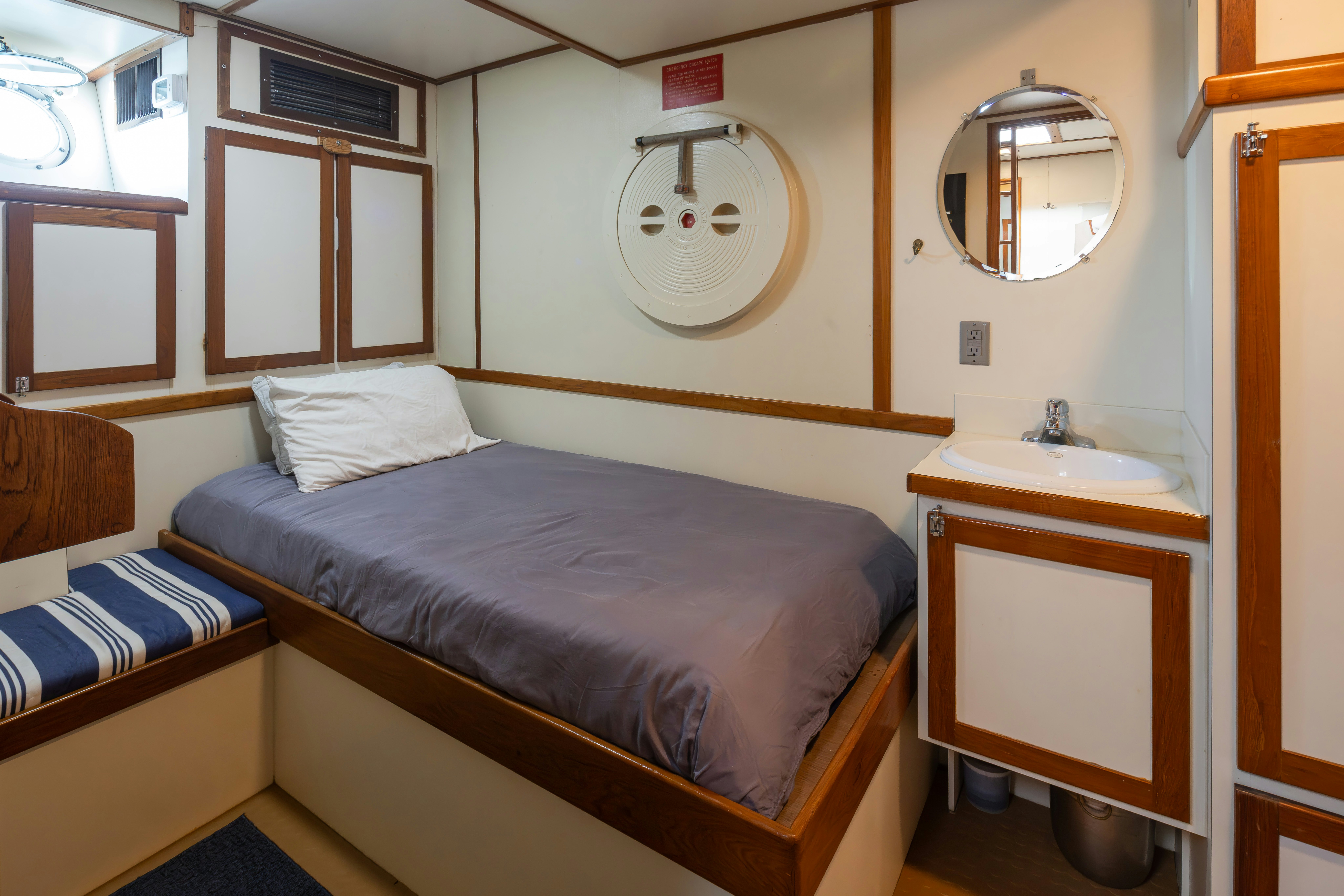 a bed with a blue bedspread and a mirror above it aboard SILVERADO Yacht for Sale