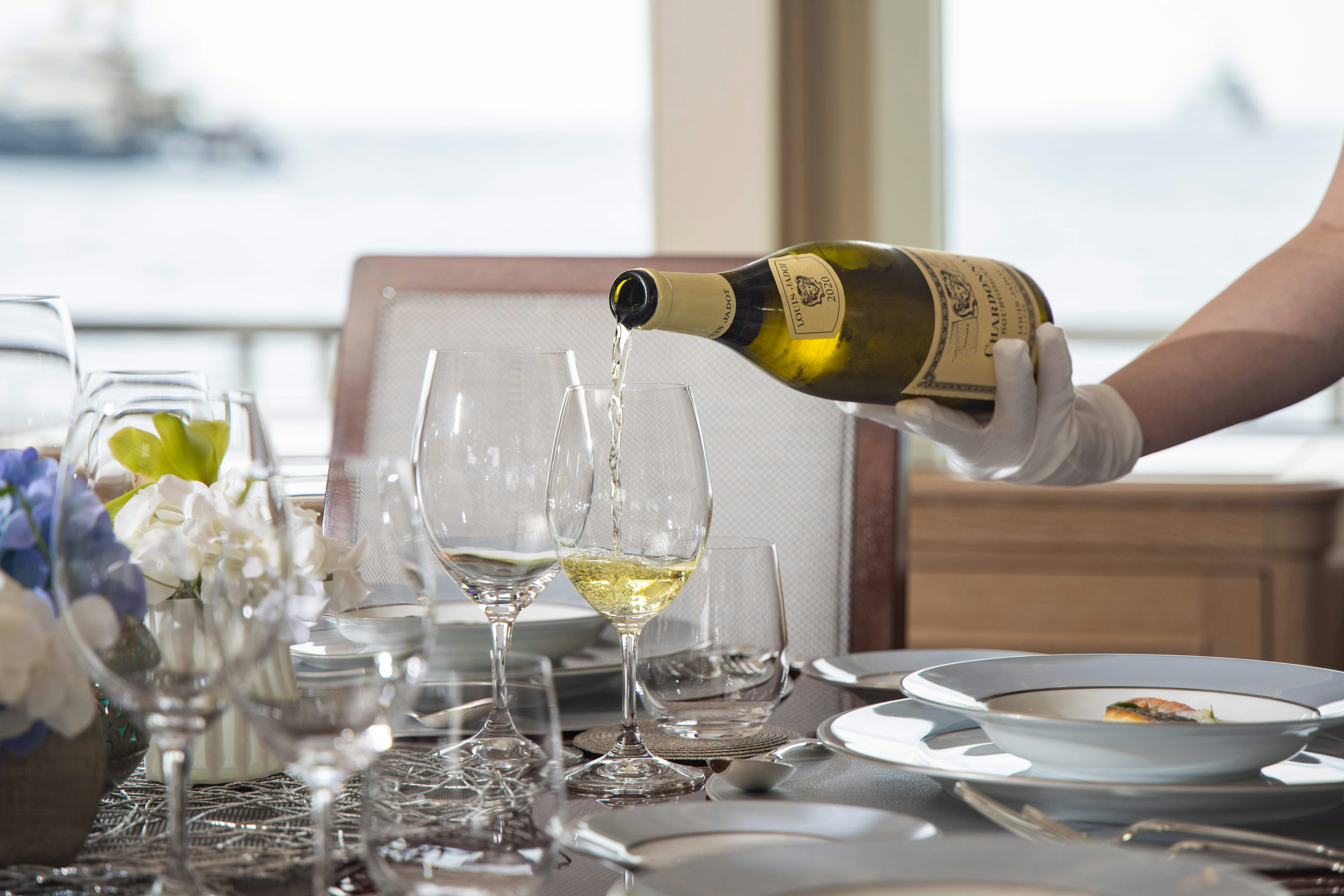a person pouring wine into a glass aboard FABULOUS CHARACTER Yacht for Charter