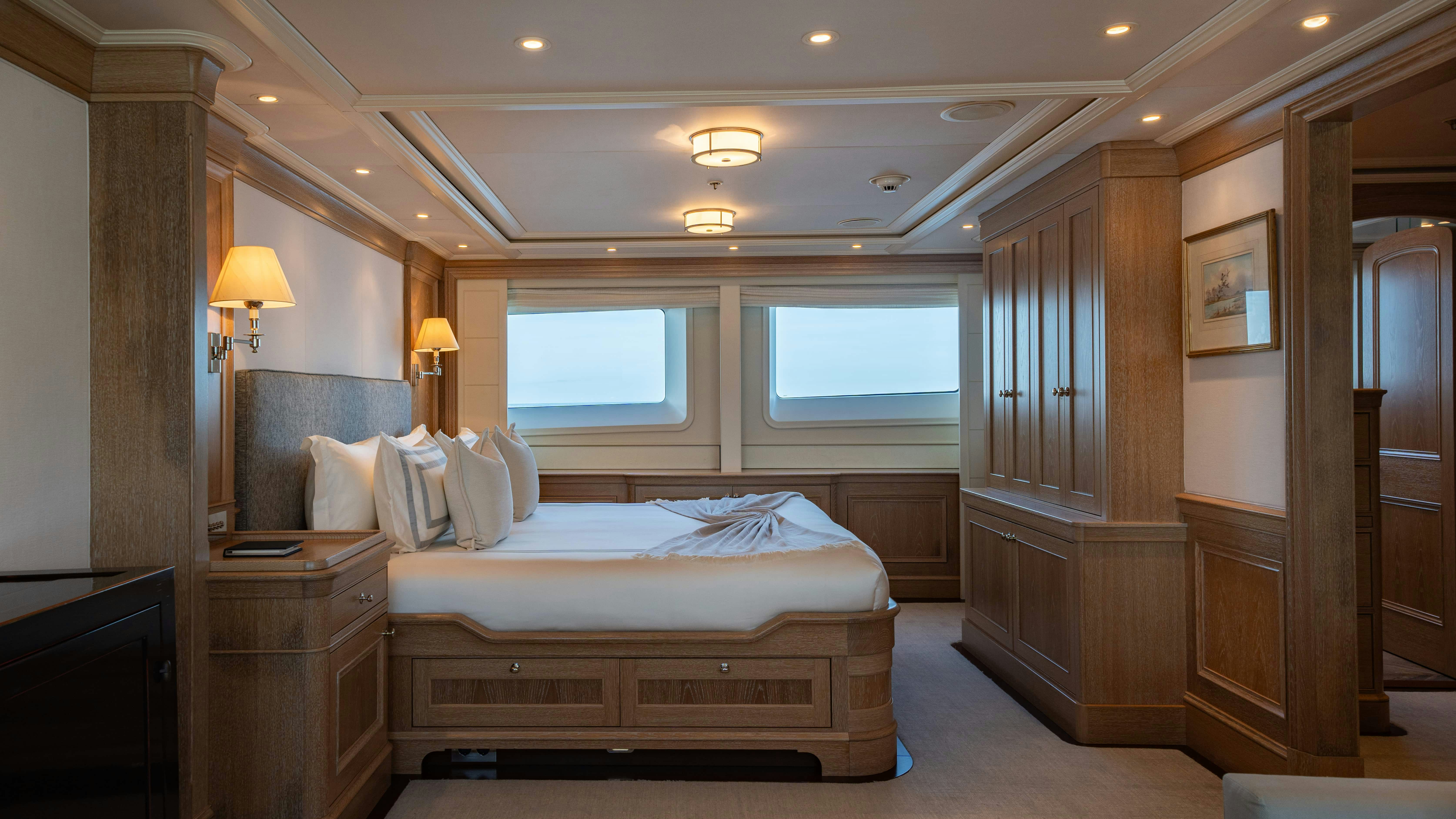 a bedroom with a bed and a wood cabinet aboard FABULOUS CHARACTER Yacht for Charter