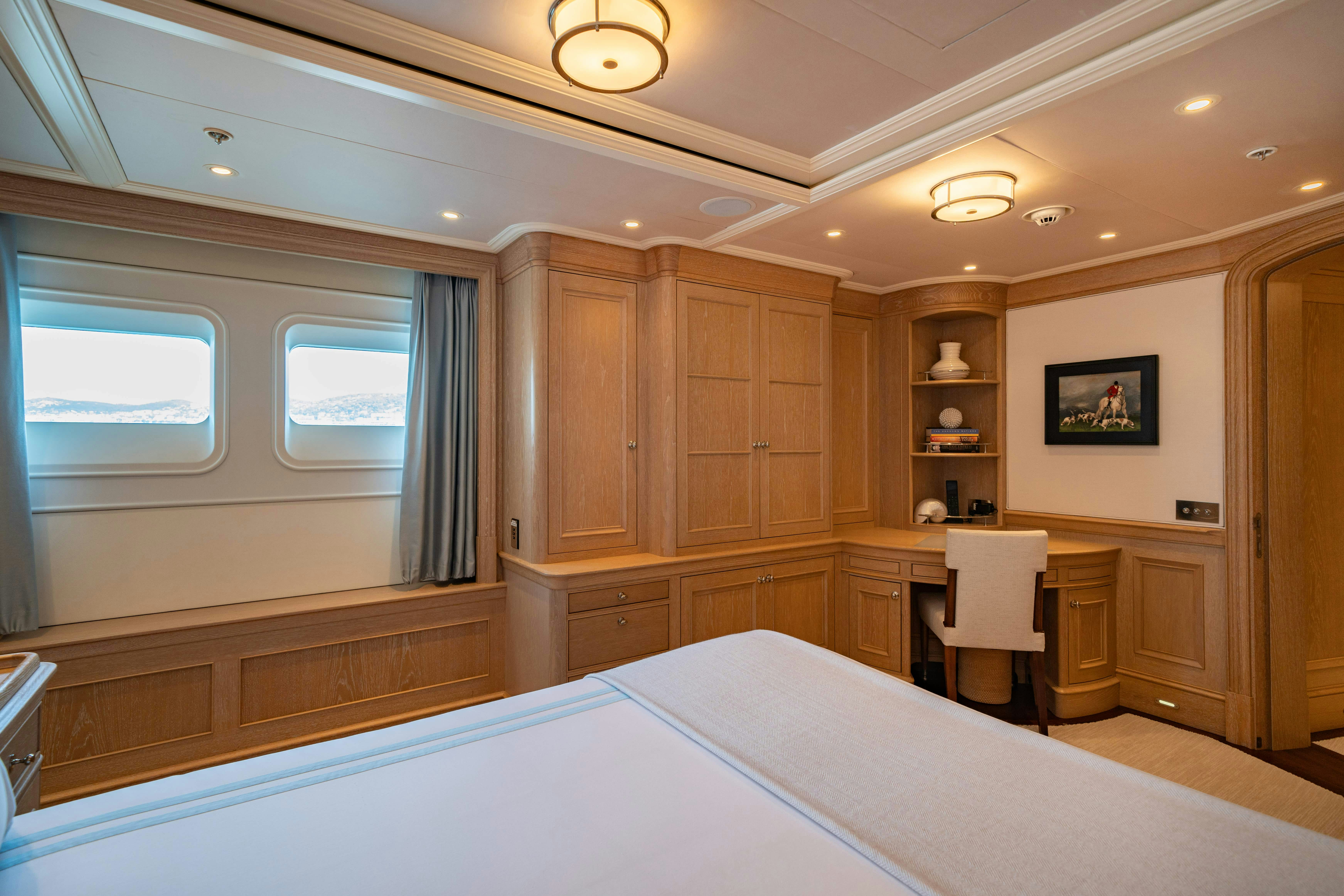 a large wooden room with a large bed and a desk aboard FABULOUS CHARACTER Yacht for Charter