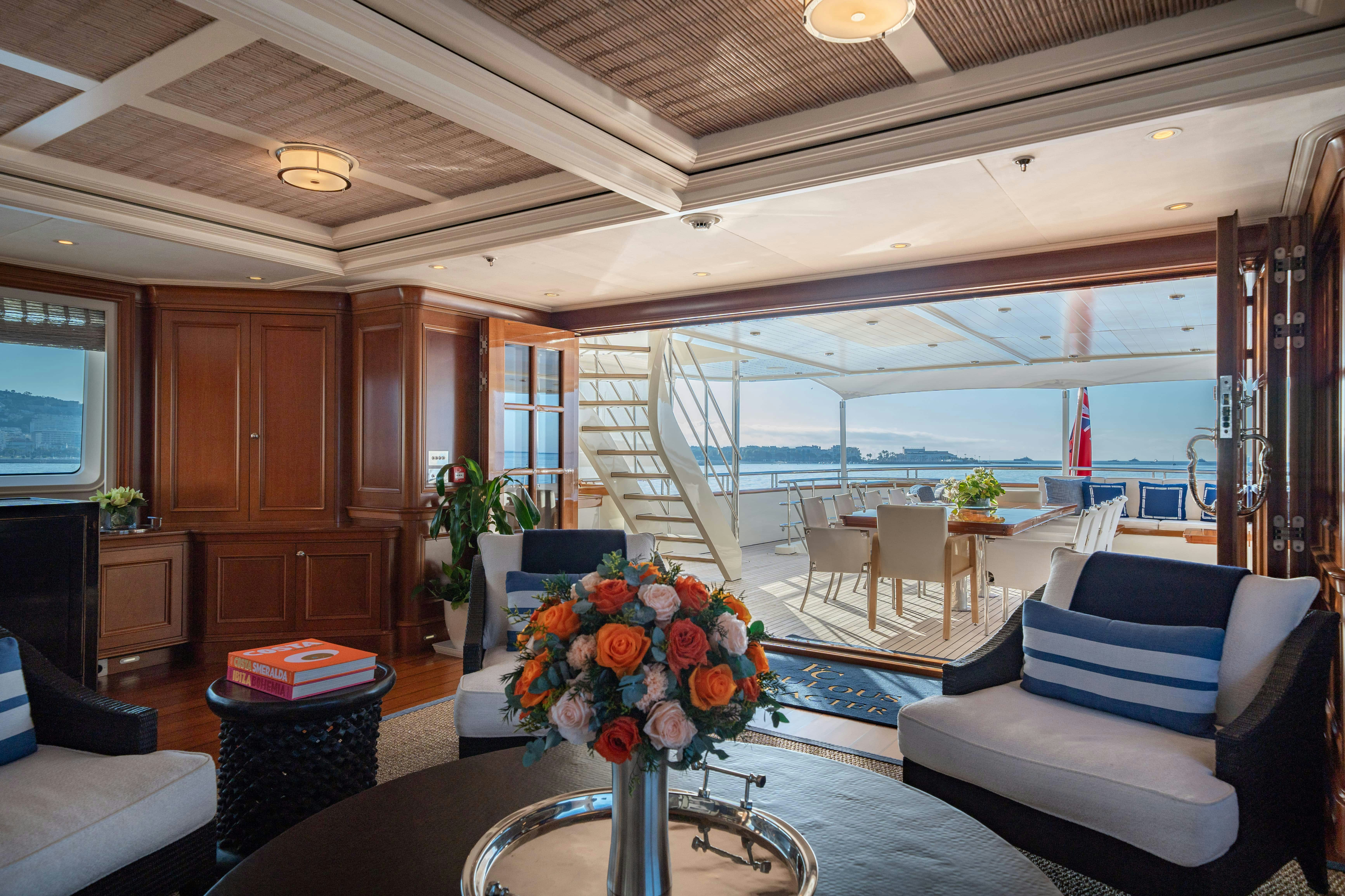 a living room with a large glass window and a table with chairs aboard FABULOUS CHARACTER Yacht for Charter