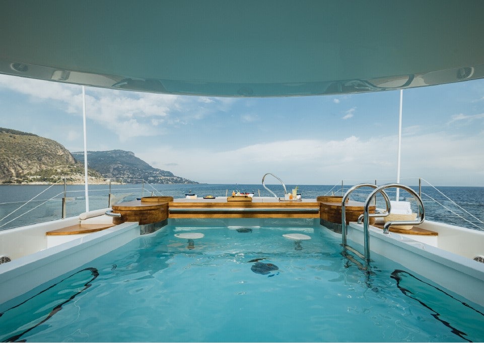 a pool with a view of mountains and water aboard VENTUM MARIS Yacht for Sale