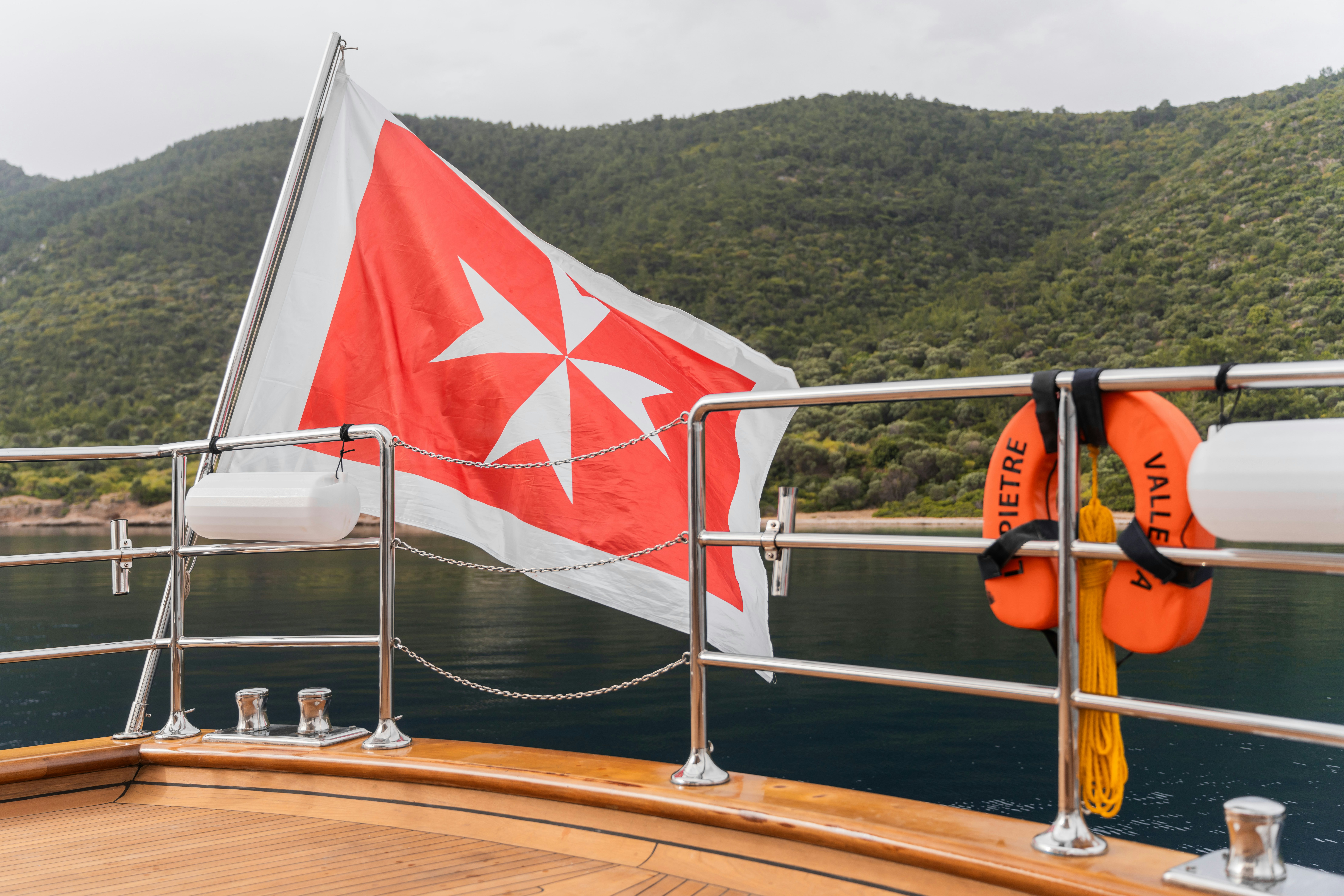a person in a life jacket on a boat with a flag aboard LE PIETRE Yacht for Sale