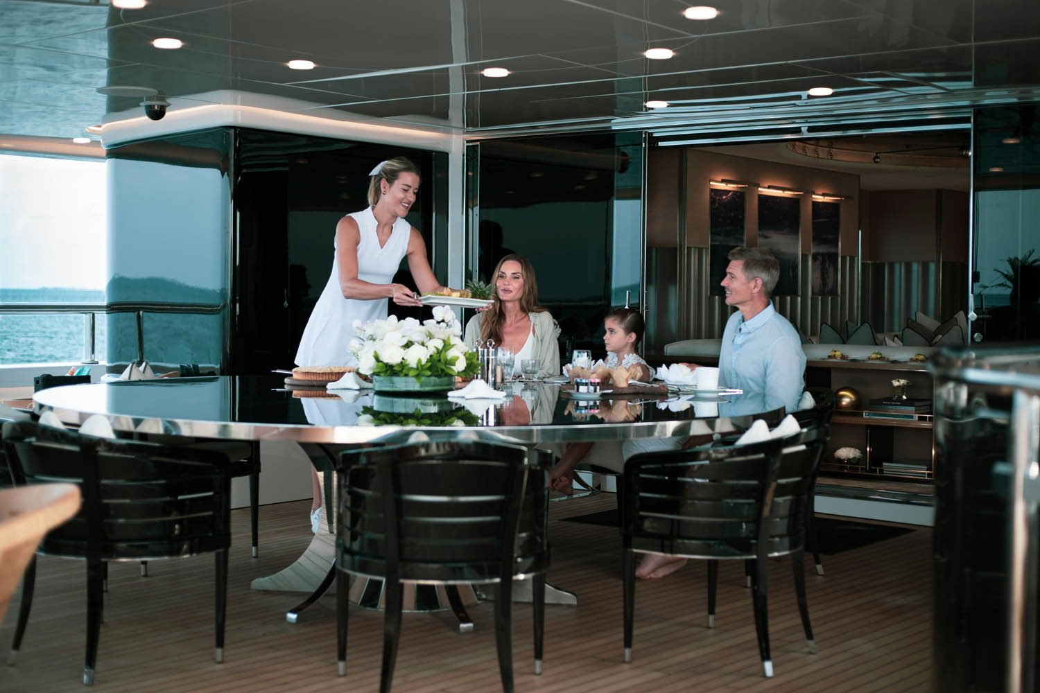a man and woman standing at a table with a man and woman sitting at it aboard SEALION Yacht for Charter
