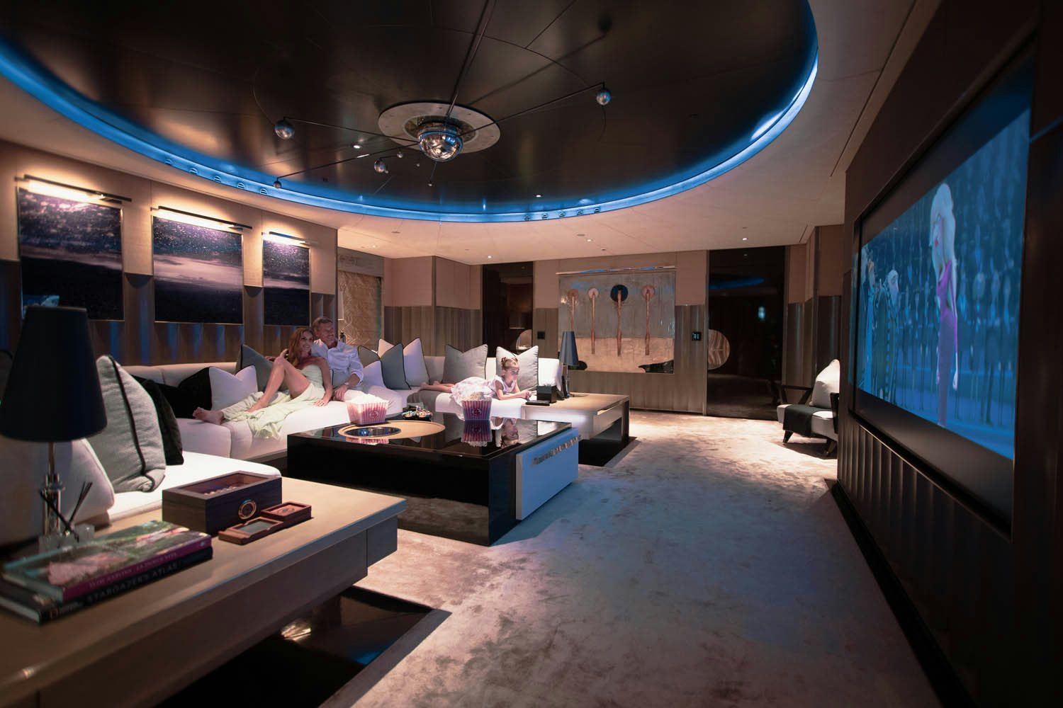 a group of people sitting on a couch in a room with a large screen aboard SEALION Yacht for Charter