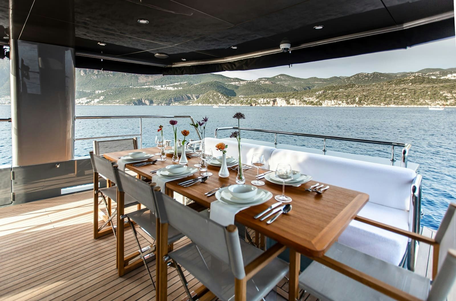 a table set for a meal on a deck overlooking a lake aboard LEVANNA Yacht for Sale