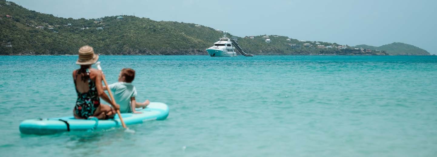 a man and a woman on a paddle board in the water aboard JUST ENOUGH Yacht for Charter
