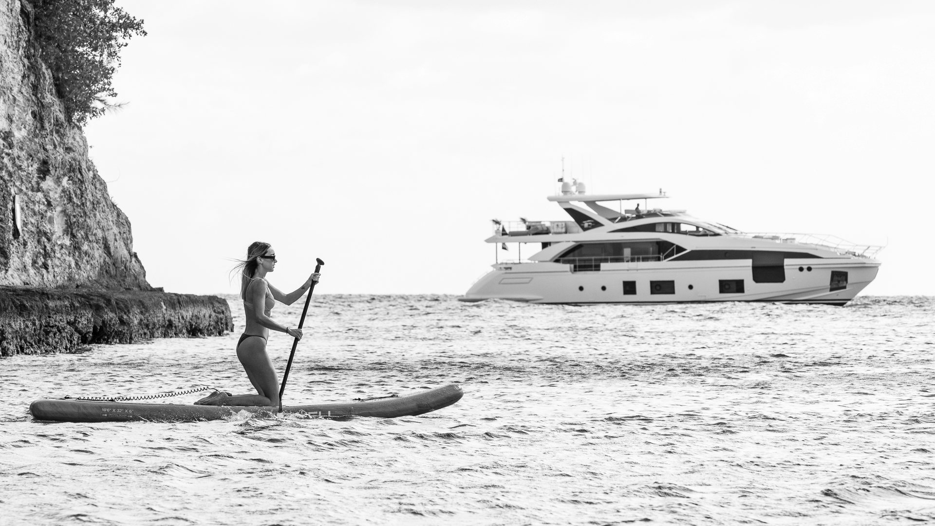 a man sitting on a beach with a boat and a large rock aboard PIER PRESSURE Yacht for Charter