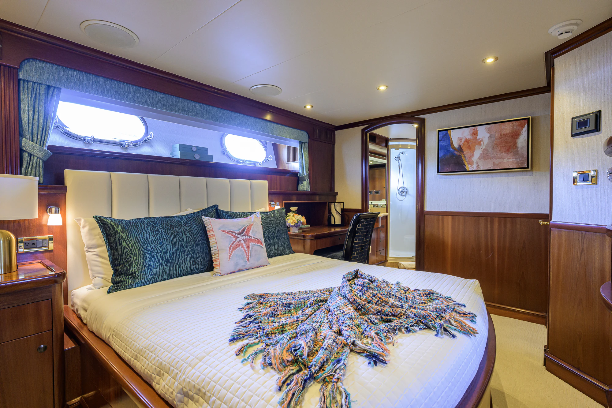 a bed with a blue and white comforter and pillows aboard MARBELLA IV Yacht for Sale