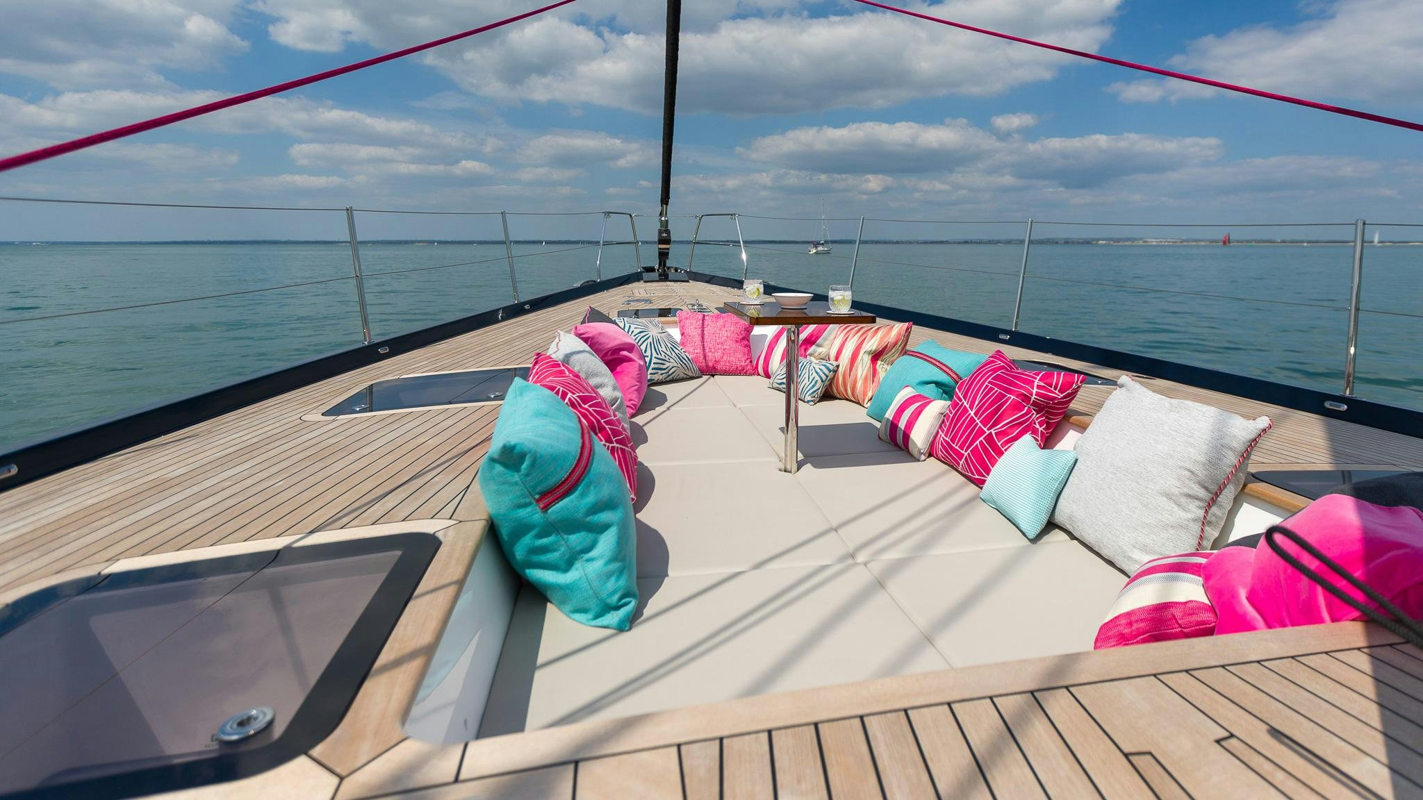 a deck with pillows and a body of water in the background aboard ACHENAR Yacht for Charter