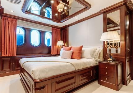 a bed with a large mirror above it aboard HEMABEJO Yacht for Charter