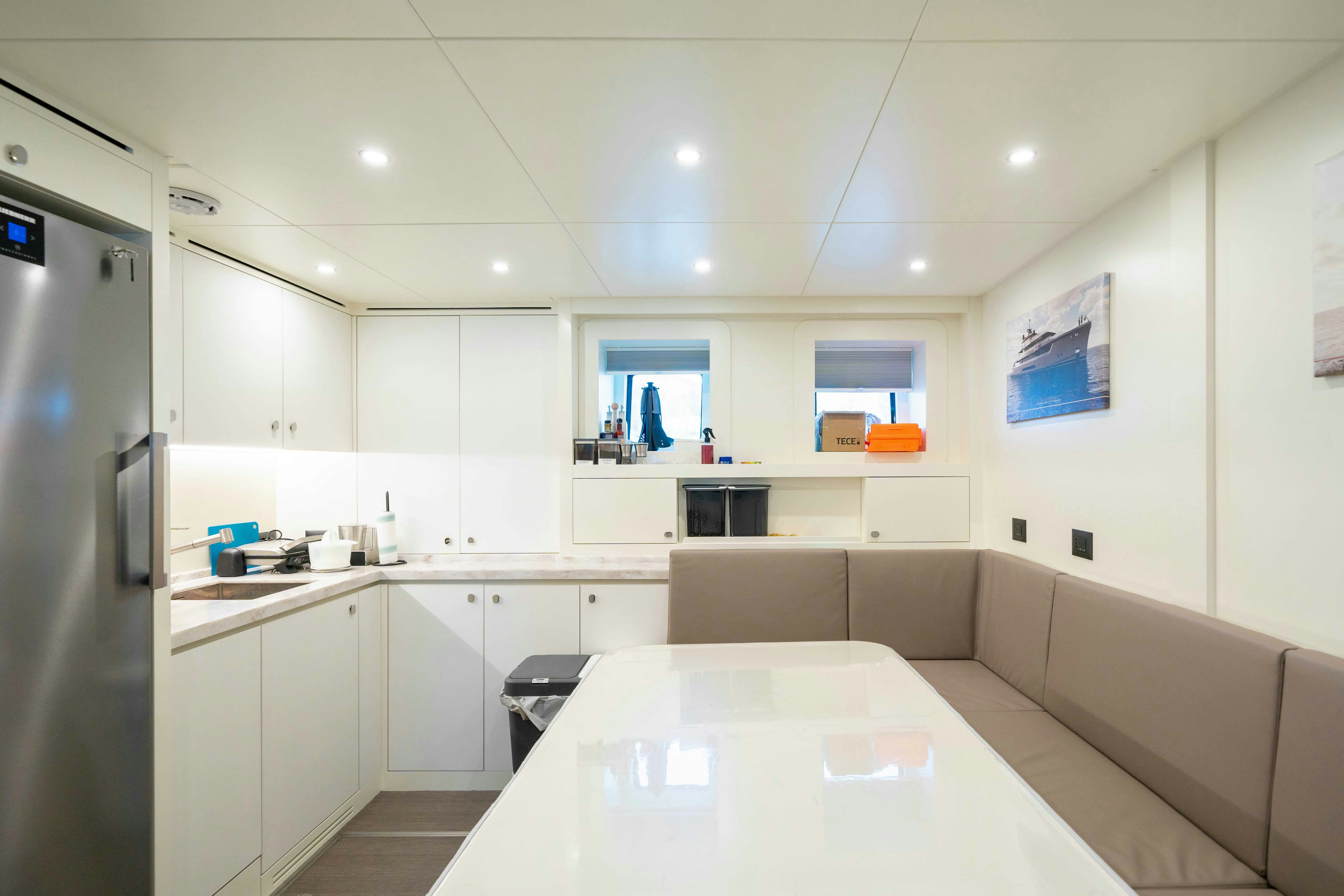 a white kitchen with a large table aboard SERENISSIMA I Yacht for Sale