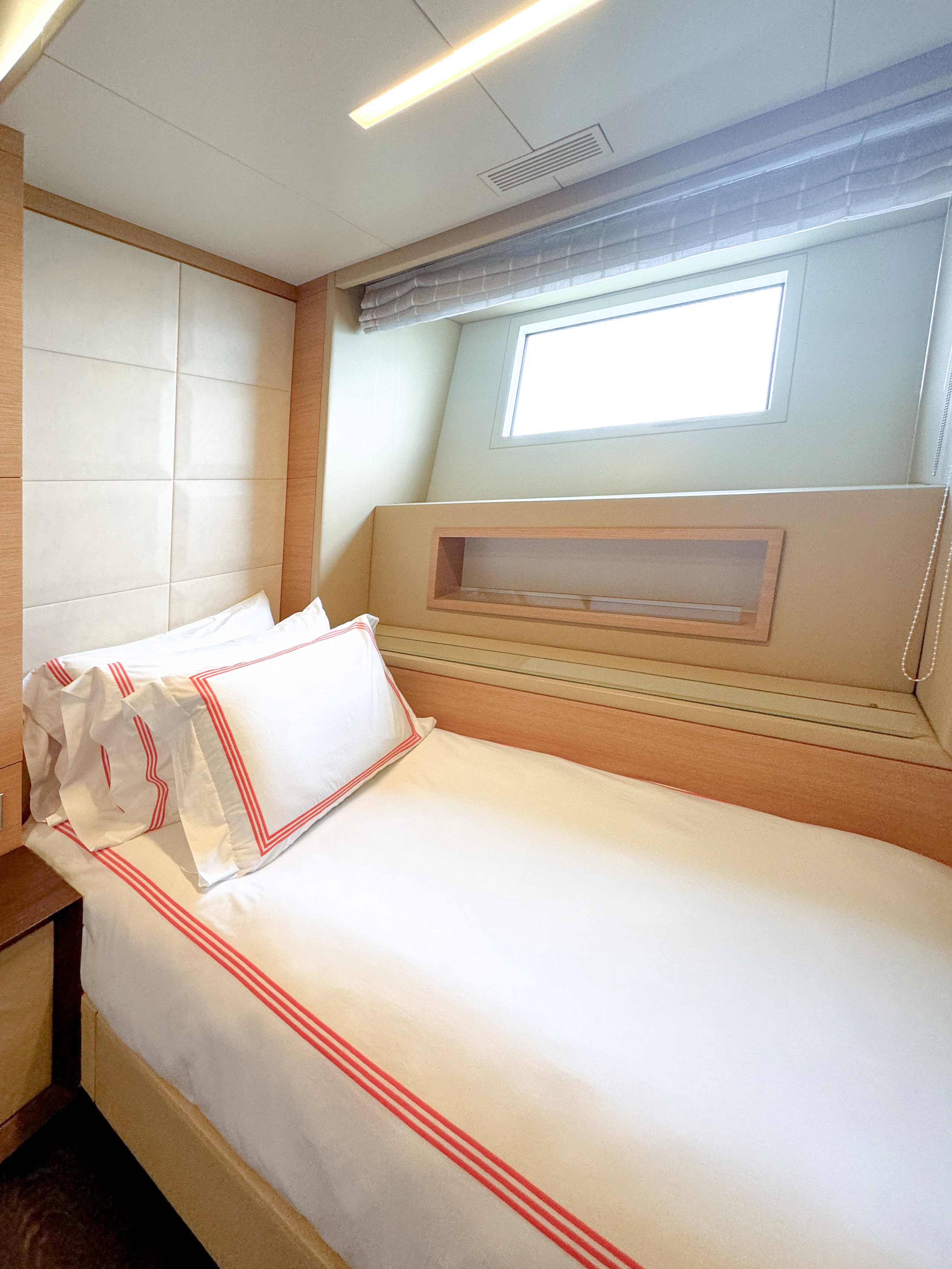 a bed with a red and white pillow on it aboard PATIENCE Yacht for Charter